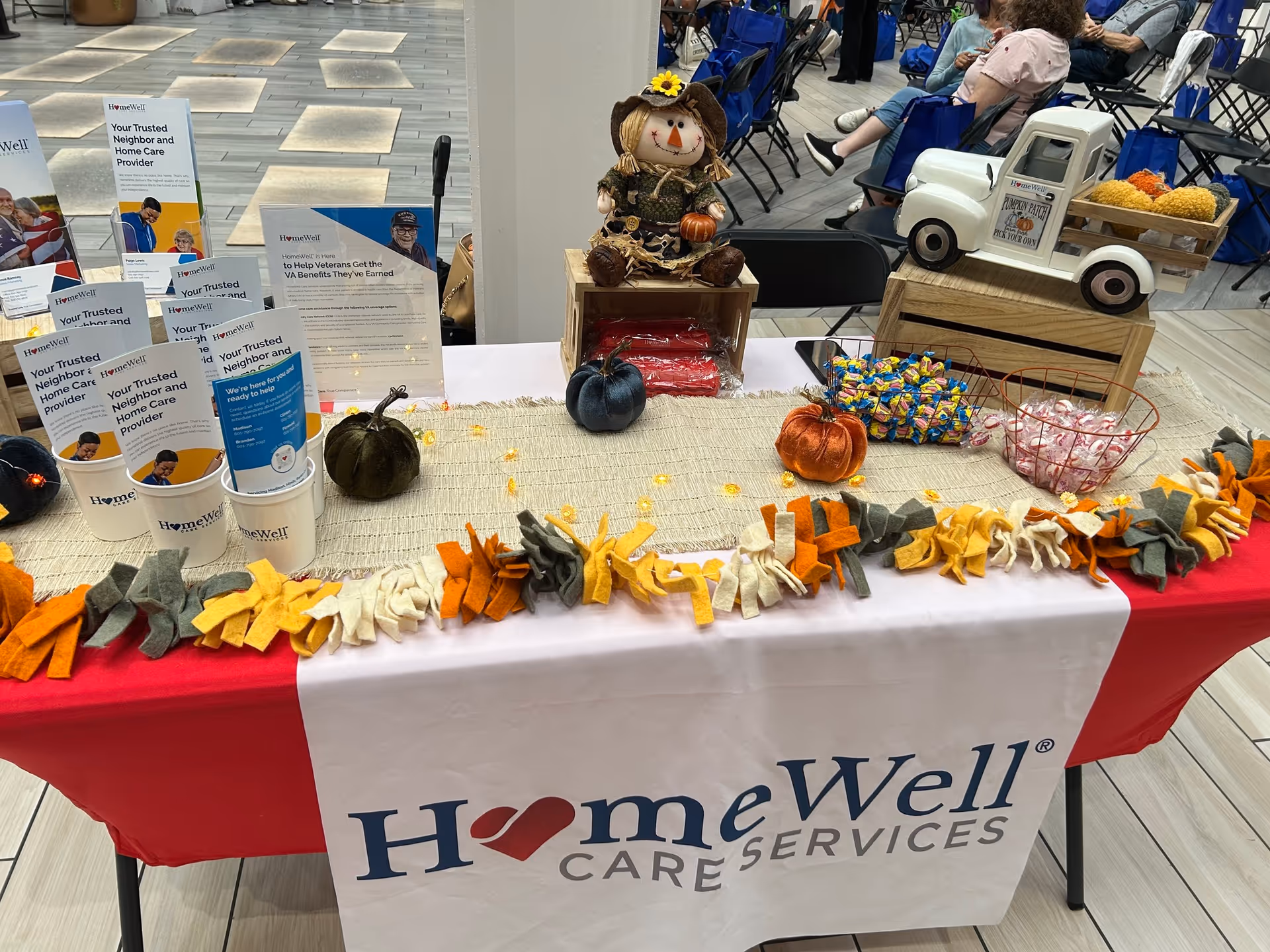 A HomeWell Care Services display table with pumpkins, fall decorations, and brochures.