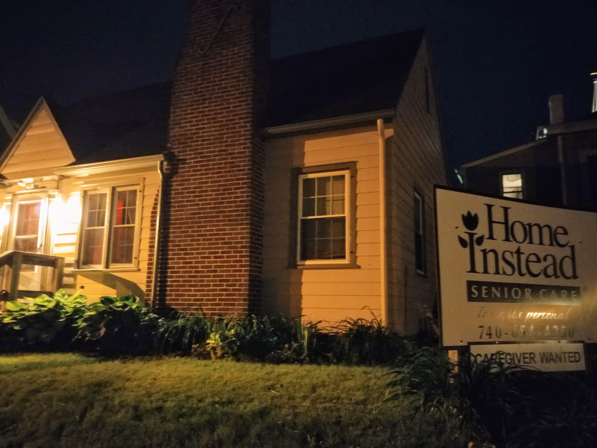 Nighttime exterior of Home Instead Senior Care building with illuminated sign