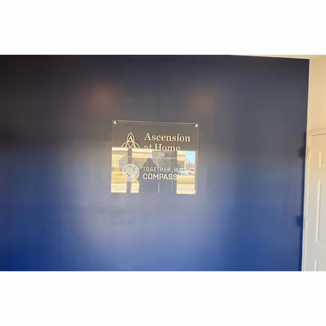 Blue interior wall with a clear plaque reading Ascension at Home Together with Compassus.