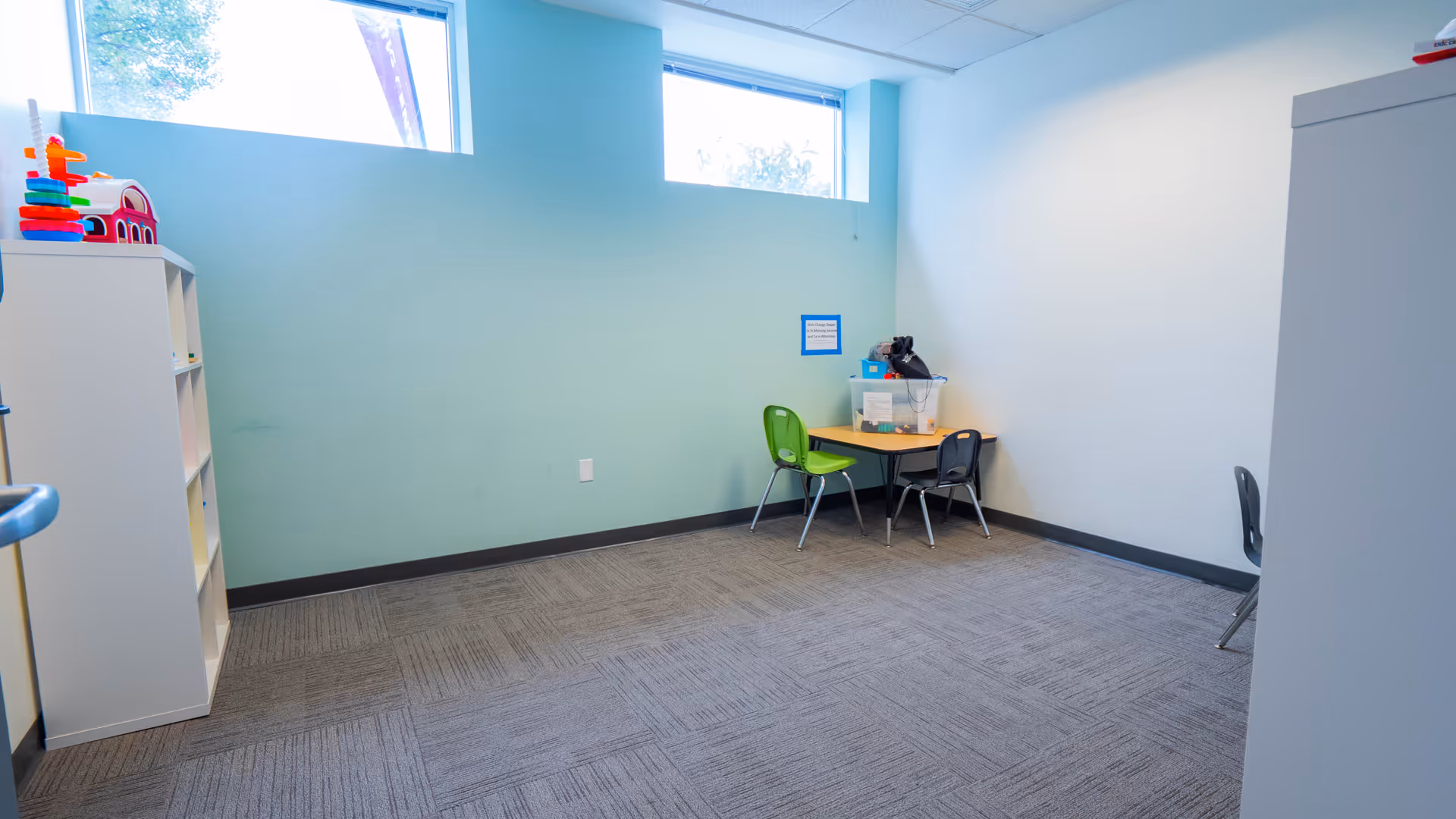 A small playroom or activity area with a table, chairs, and toy shelves.