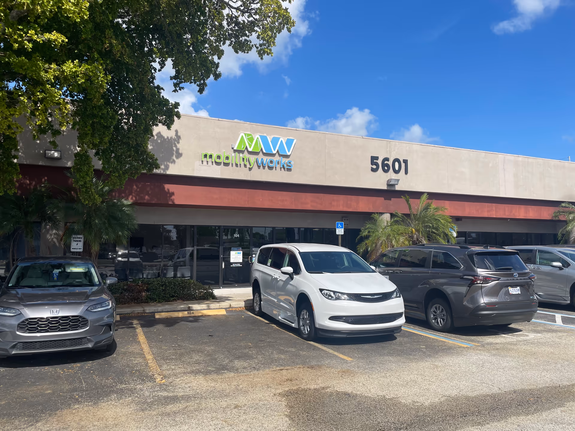 Front of MobilityWorks facility with parking lot, signage, and a blue sky above.