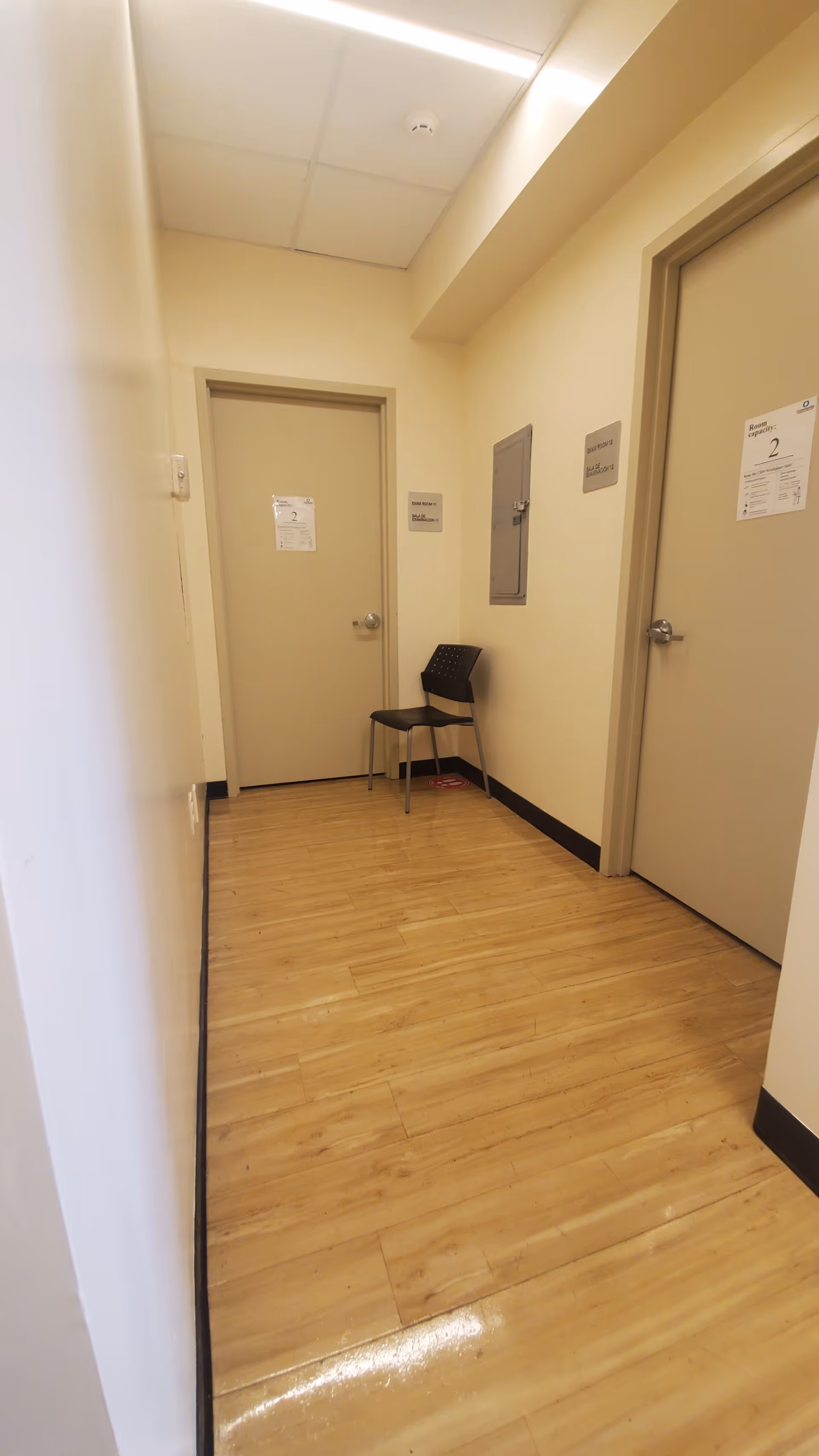 Narrow hallway inside a senior living facility with closed doors and a chair.