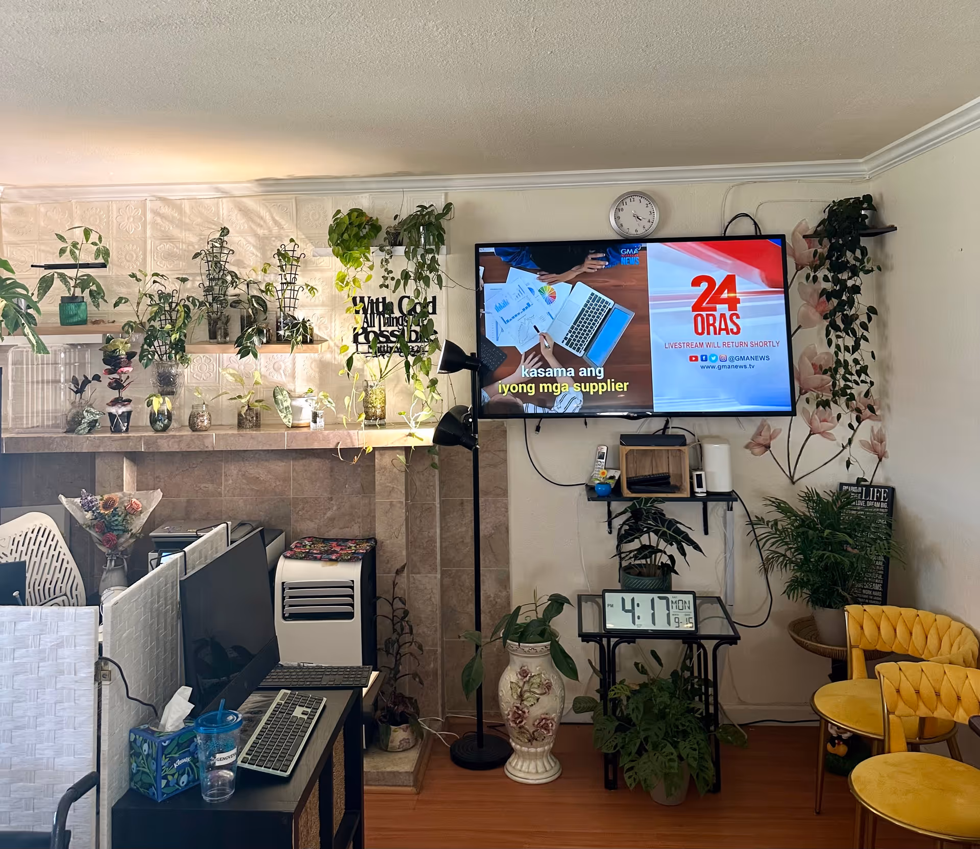 Indoor common area with a wall-mounted TV, plants, and seating at Anchor Elderly Care Home.