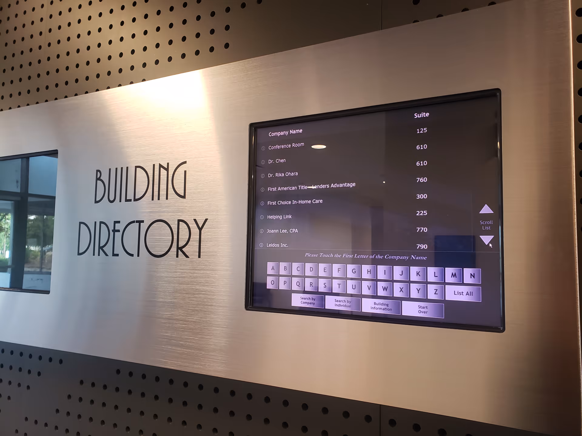 Metal wall with a large Building Directory sign and a digital listing screen.