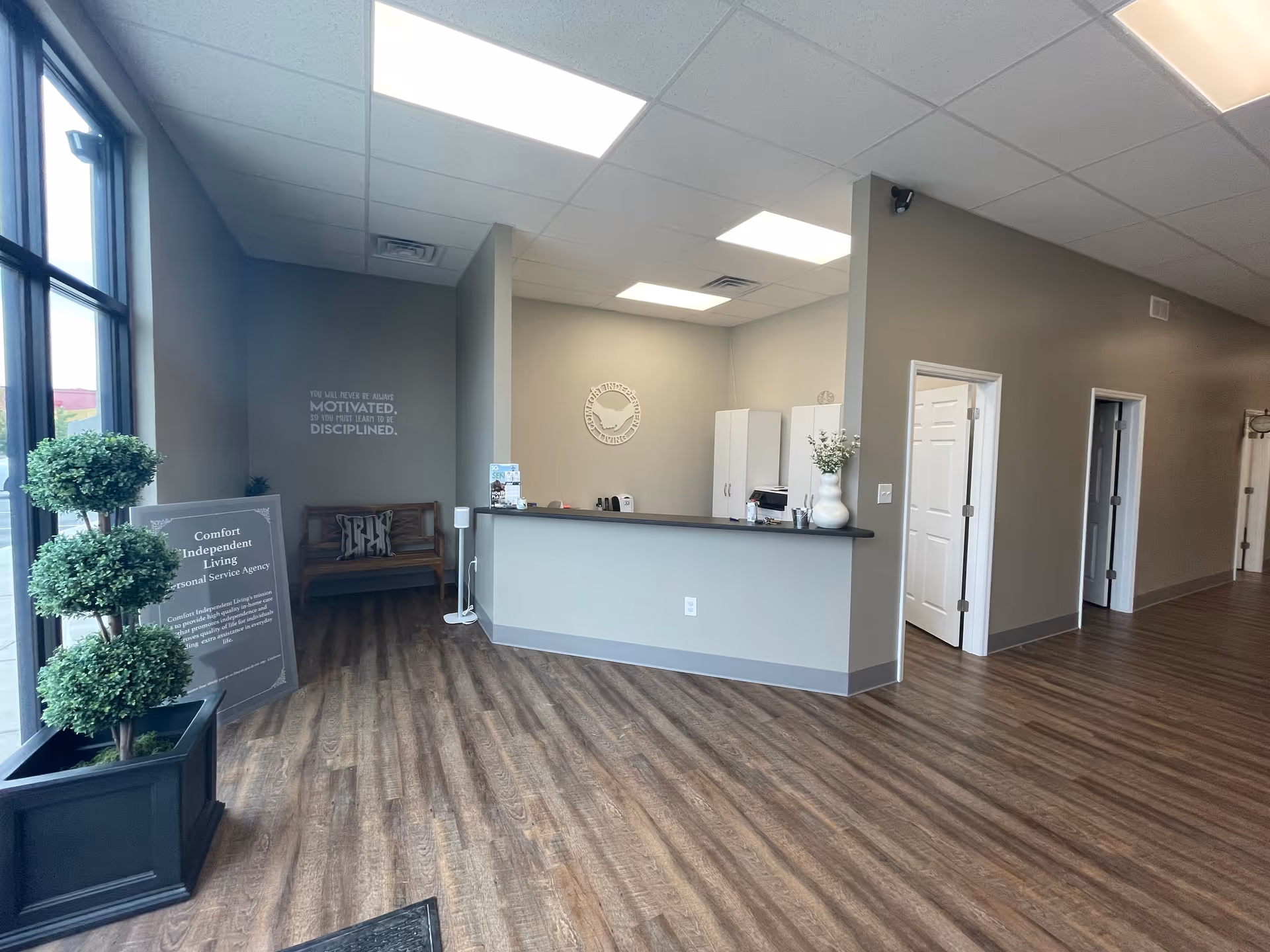 Reception area of Comfort Independent Living with a front desk, seating, and large windows.