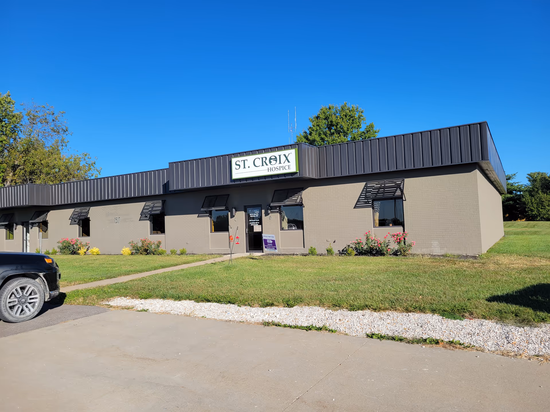 Single-story beige facility with St. Croix Hospice sign, blue sky, and parking lot.