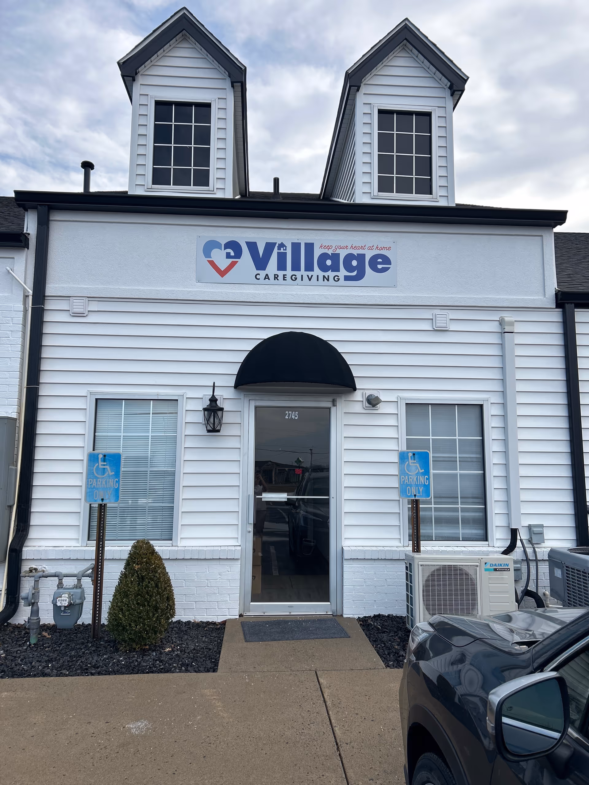 White, two-story building with Village Caregiving sign and front entrance.