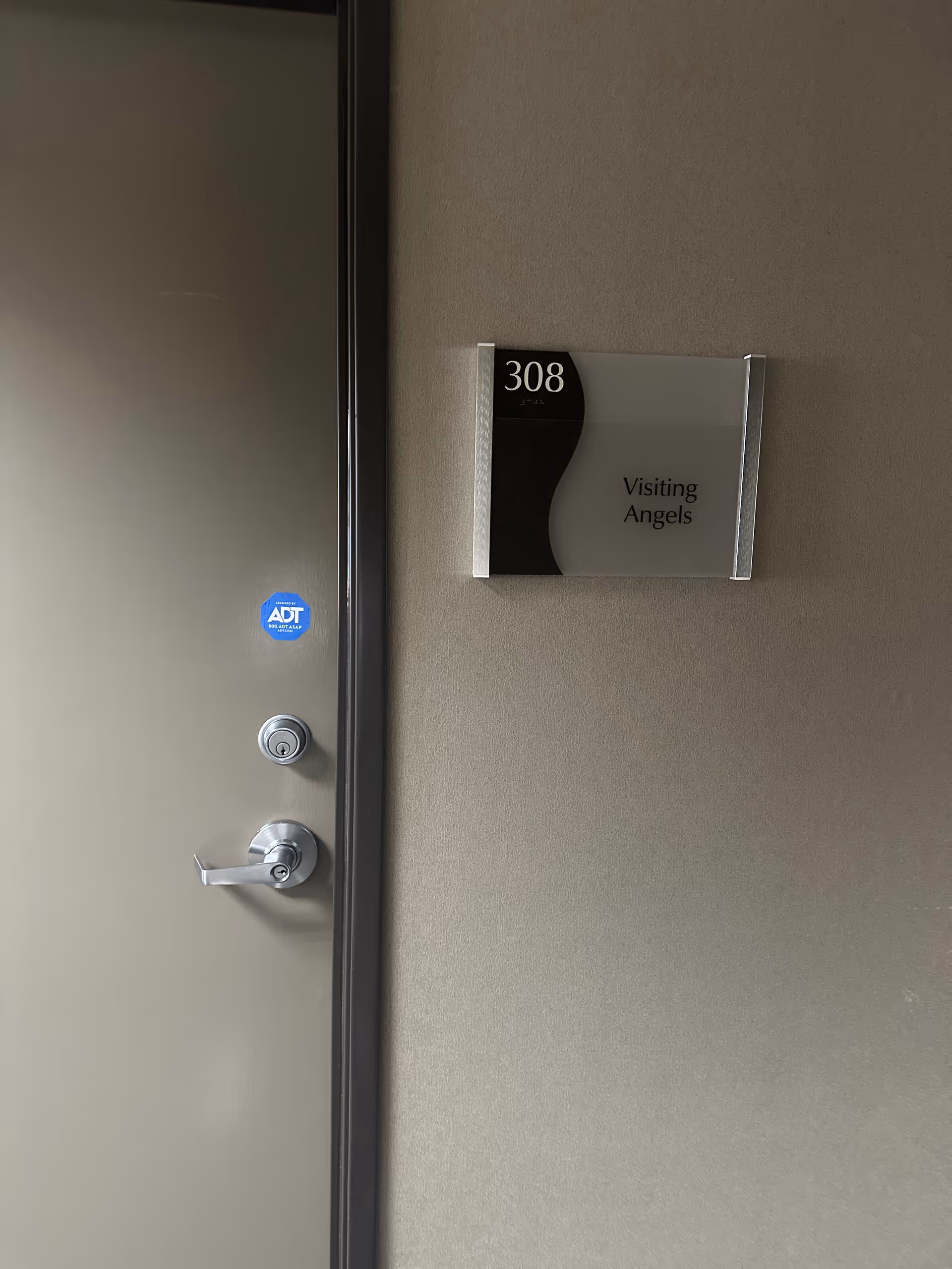 A hallway interior door with a wall plaque reading Visiting Angels and room 308