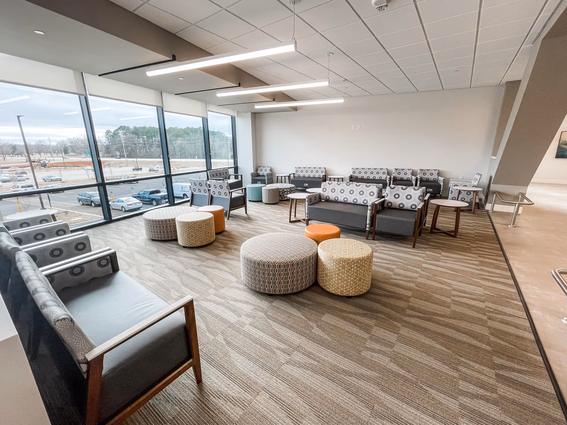 Bright Ozarks Healthcare at Home lounge with patterned seating and large windows overlooking parking.