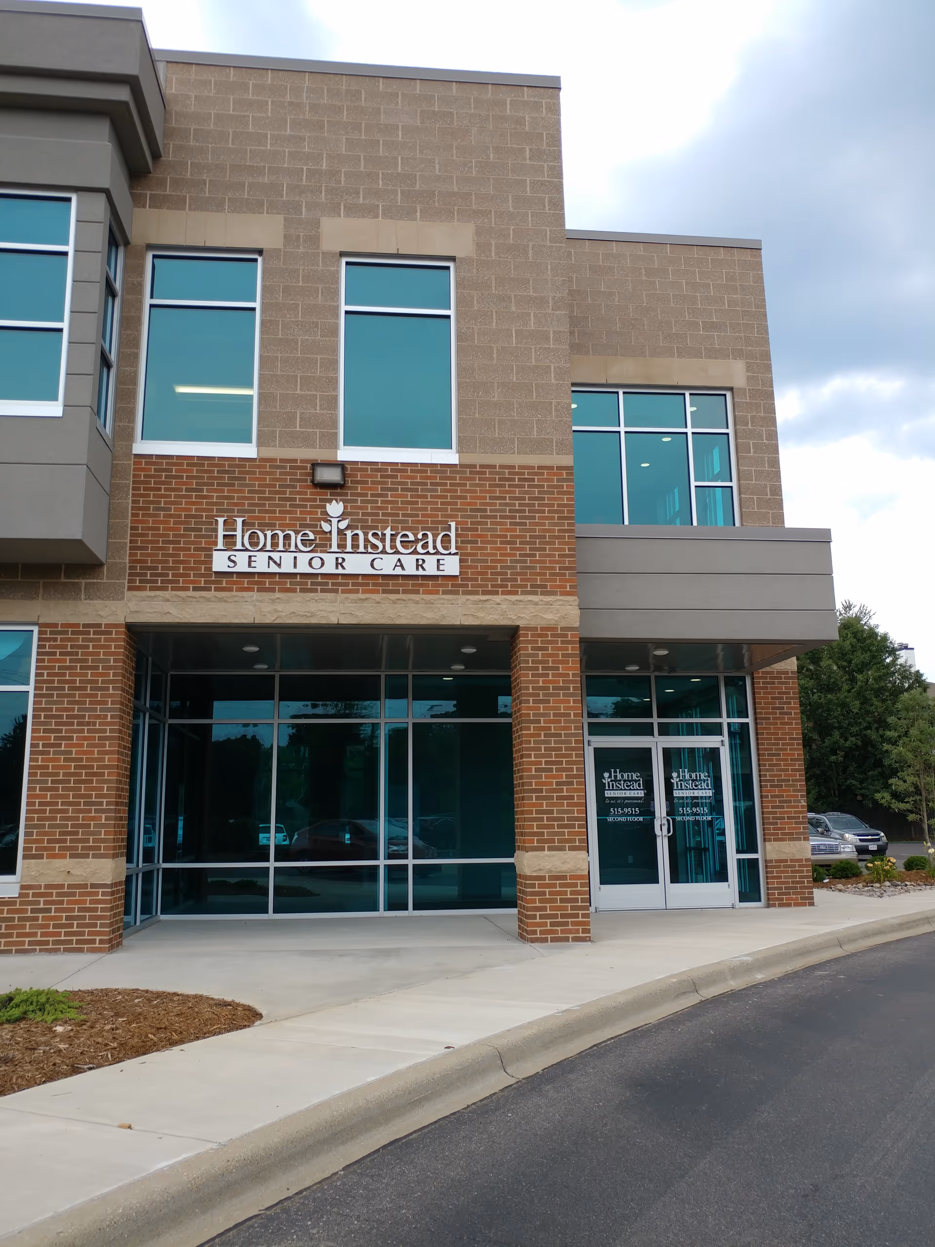 Exterior of a Home Instead Senior Care facility with brick facade and glass entrance.