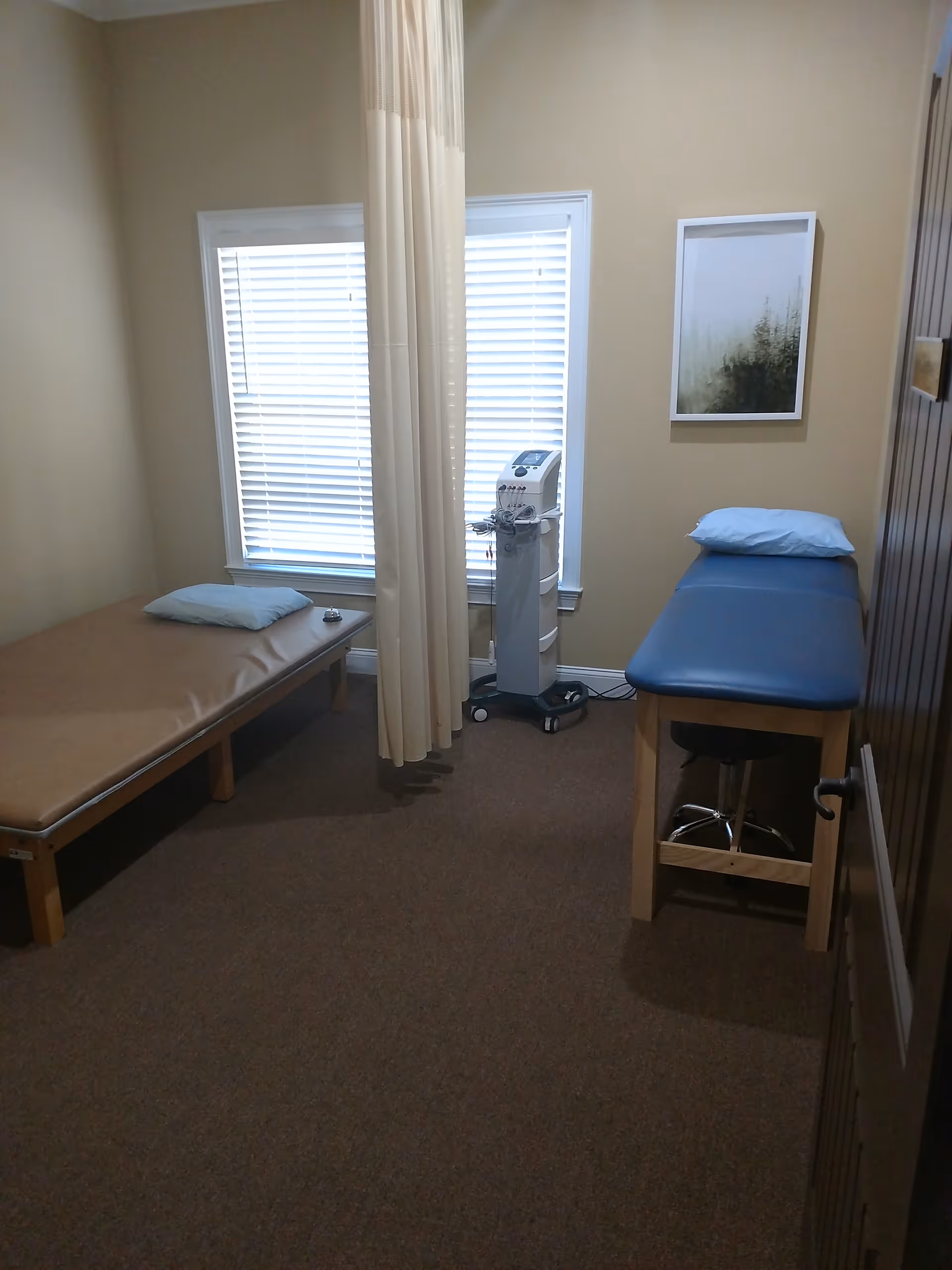 Interior clinic room with two beds, a privacy curtain, and medical equipment.