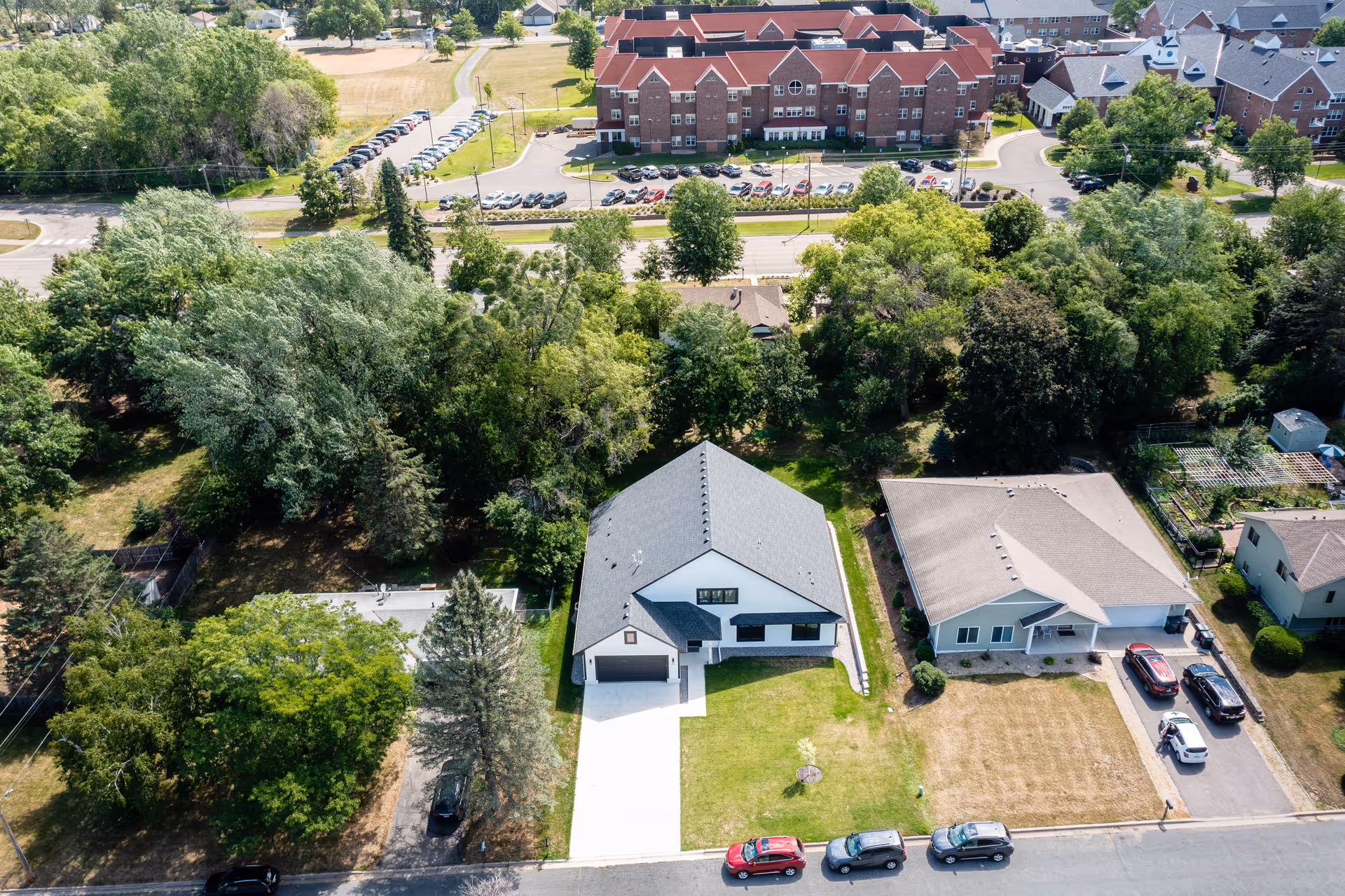 Aerial exterior view of a suburban neighborhood with a modern house and surrounding trees