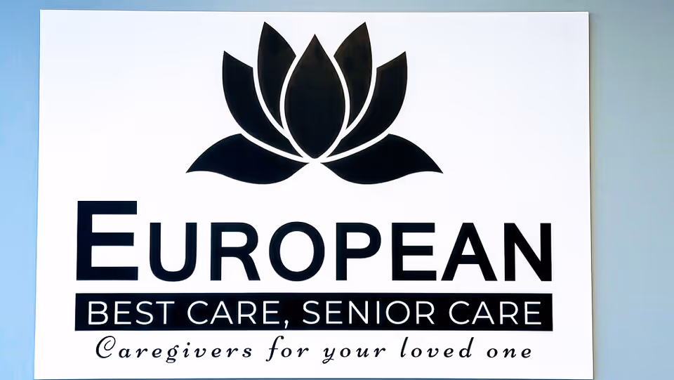 White wall sign with lotus logo, 'EUROPEAN BEST CARE' and 'Caregivers for your loved one' slogan.