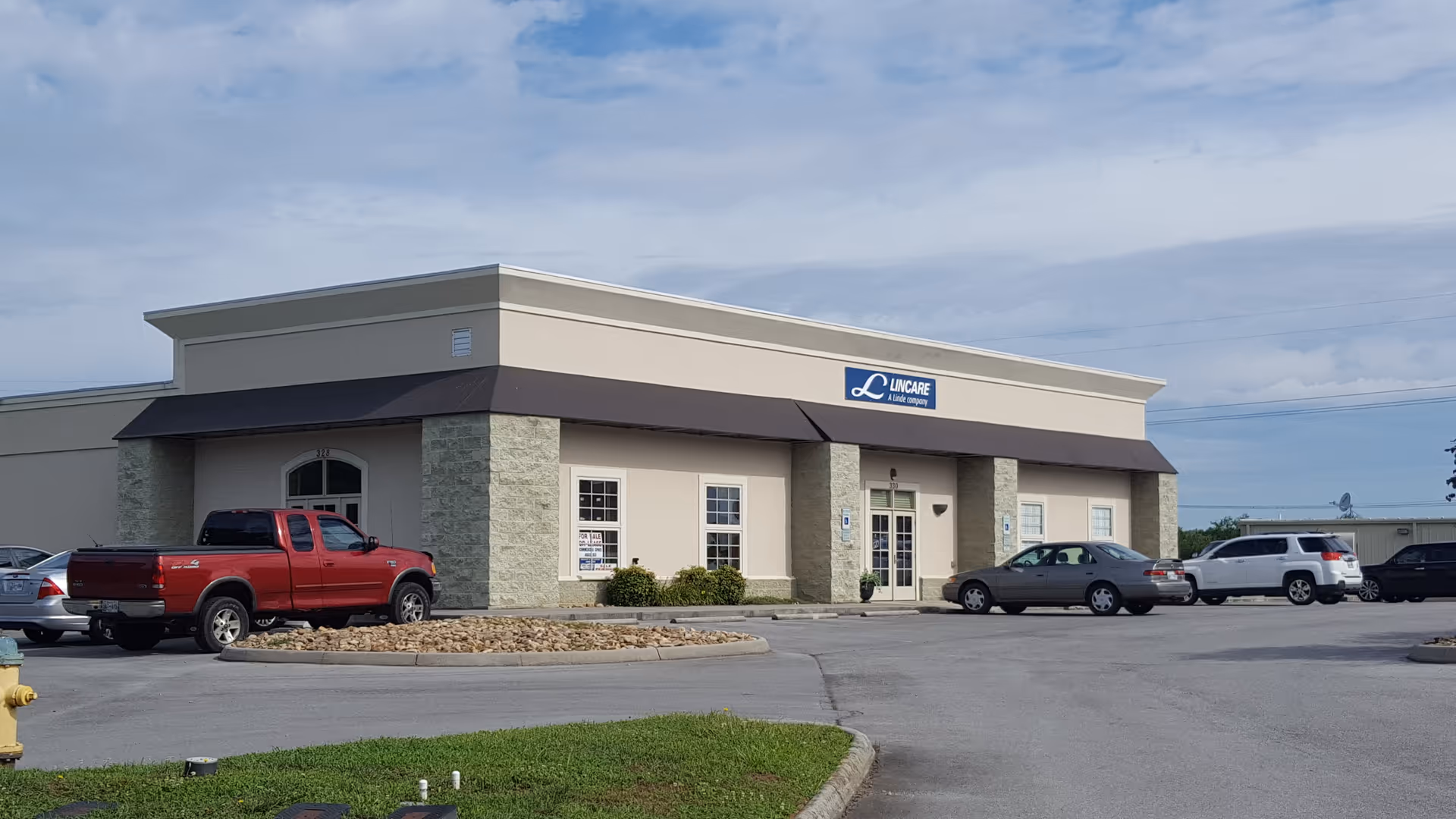Exterior view of a LINCARE building with a parking lot, front entrance and beige facade
