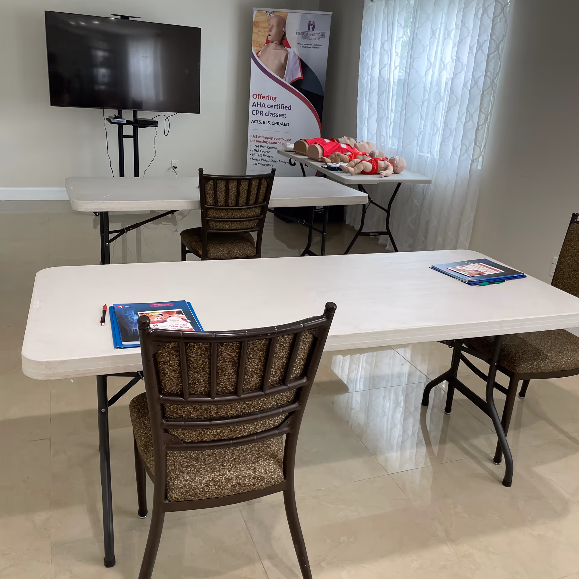 Training room with tables, chairs, CPR mannequins, and a promotional banner.