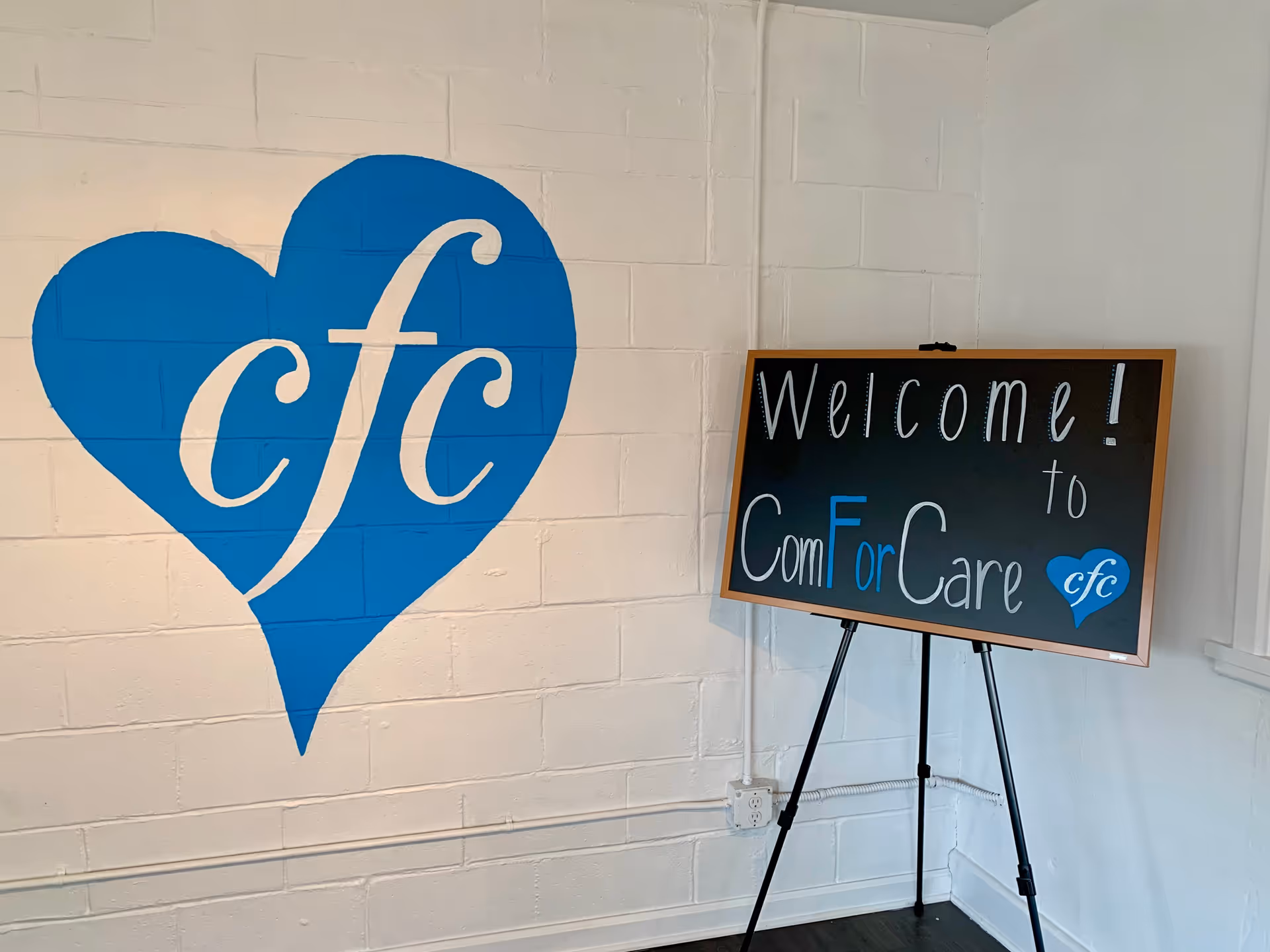 Interior lobby area with blue heart logo mural and welcome sign for ComForCare.