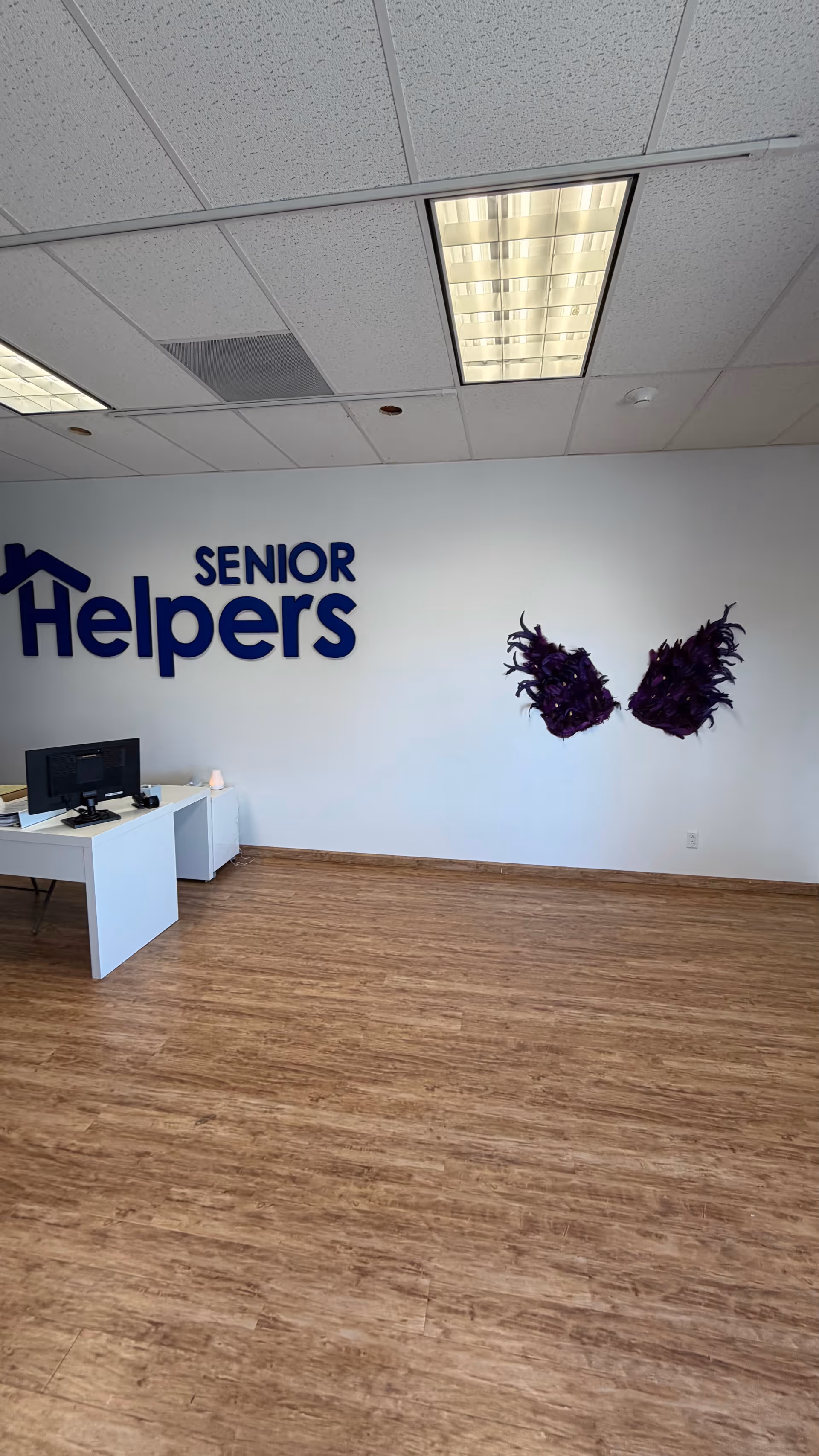 Reception area inside Senior Helpers with a desk and purple wing wall decor.
