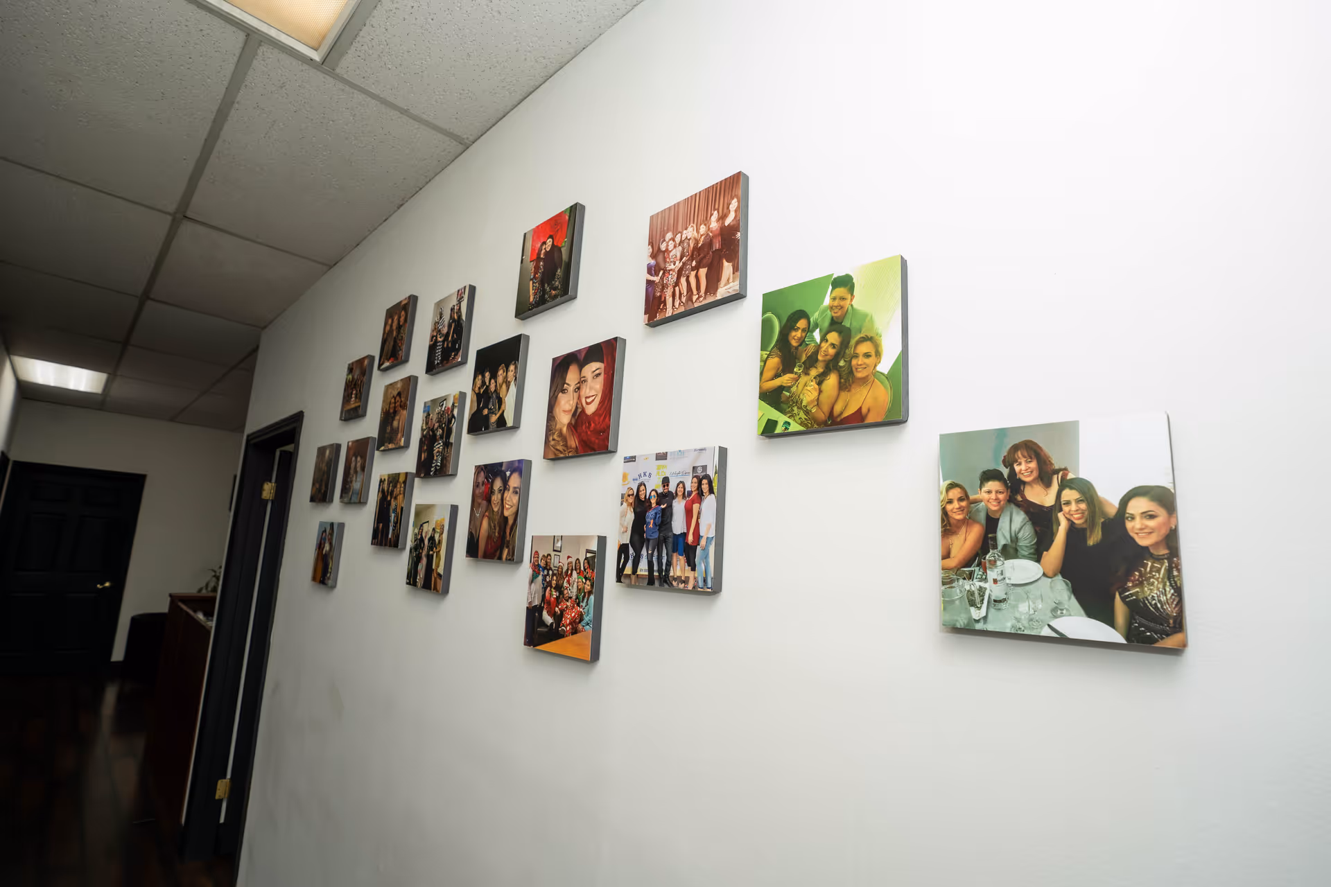 White hallway with multiple framed group photos arranged along the wall.