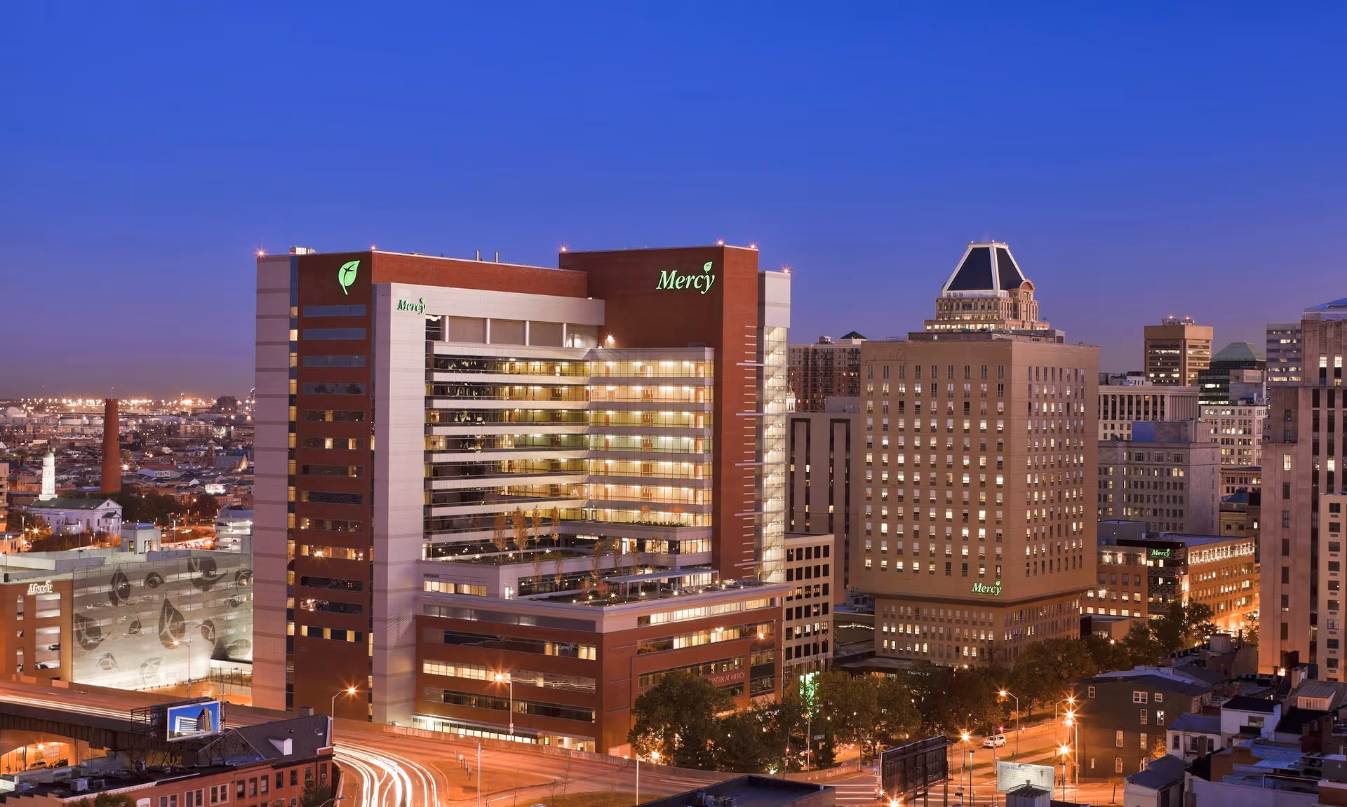 Dusk view of Mercy Medical Center buildings illuminated in a city skyline