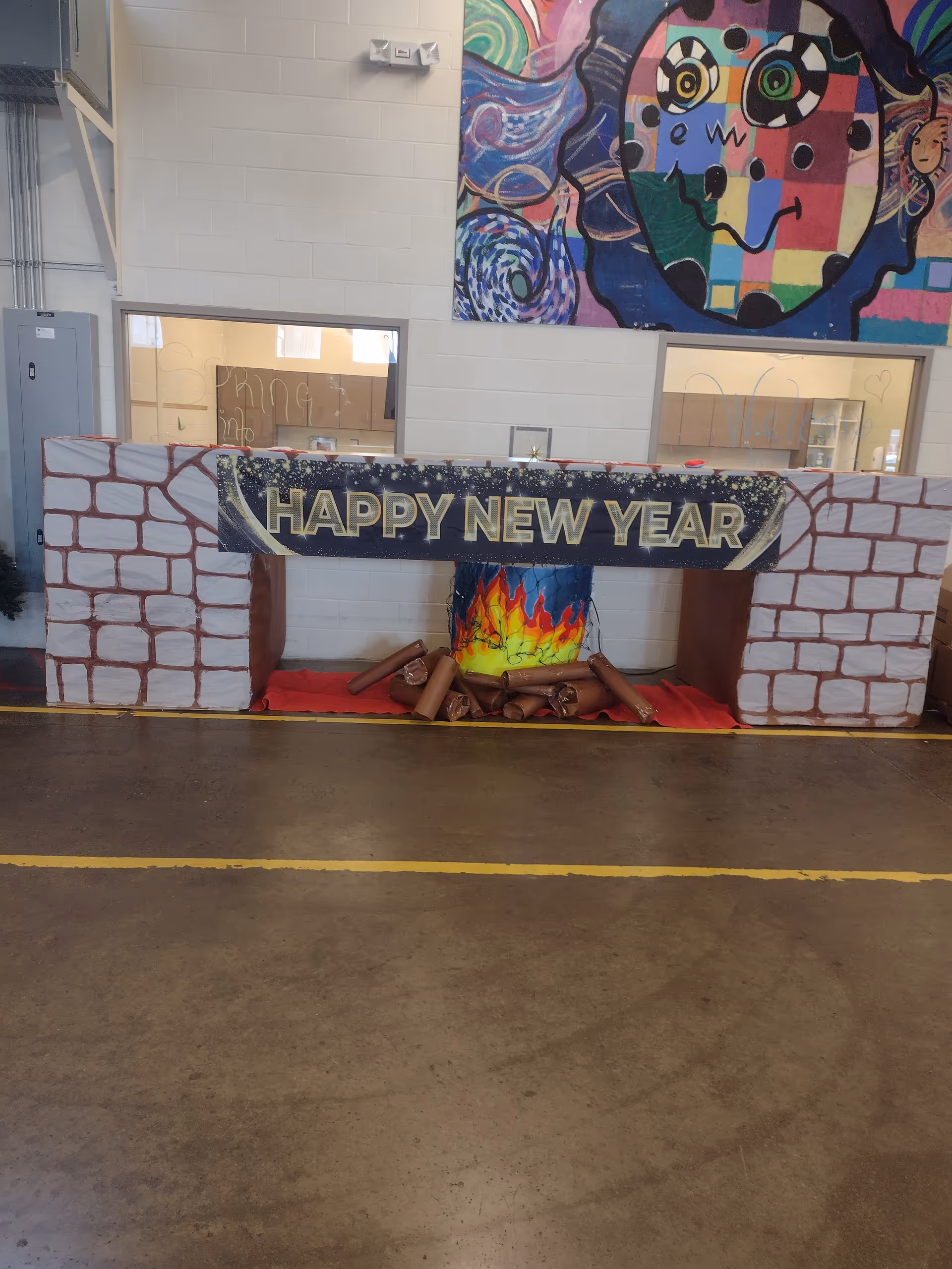 Indoor hallway with a decorative 'Happy New Year' fireplace display and colorful mural.