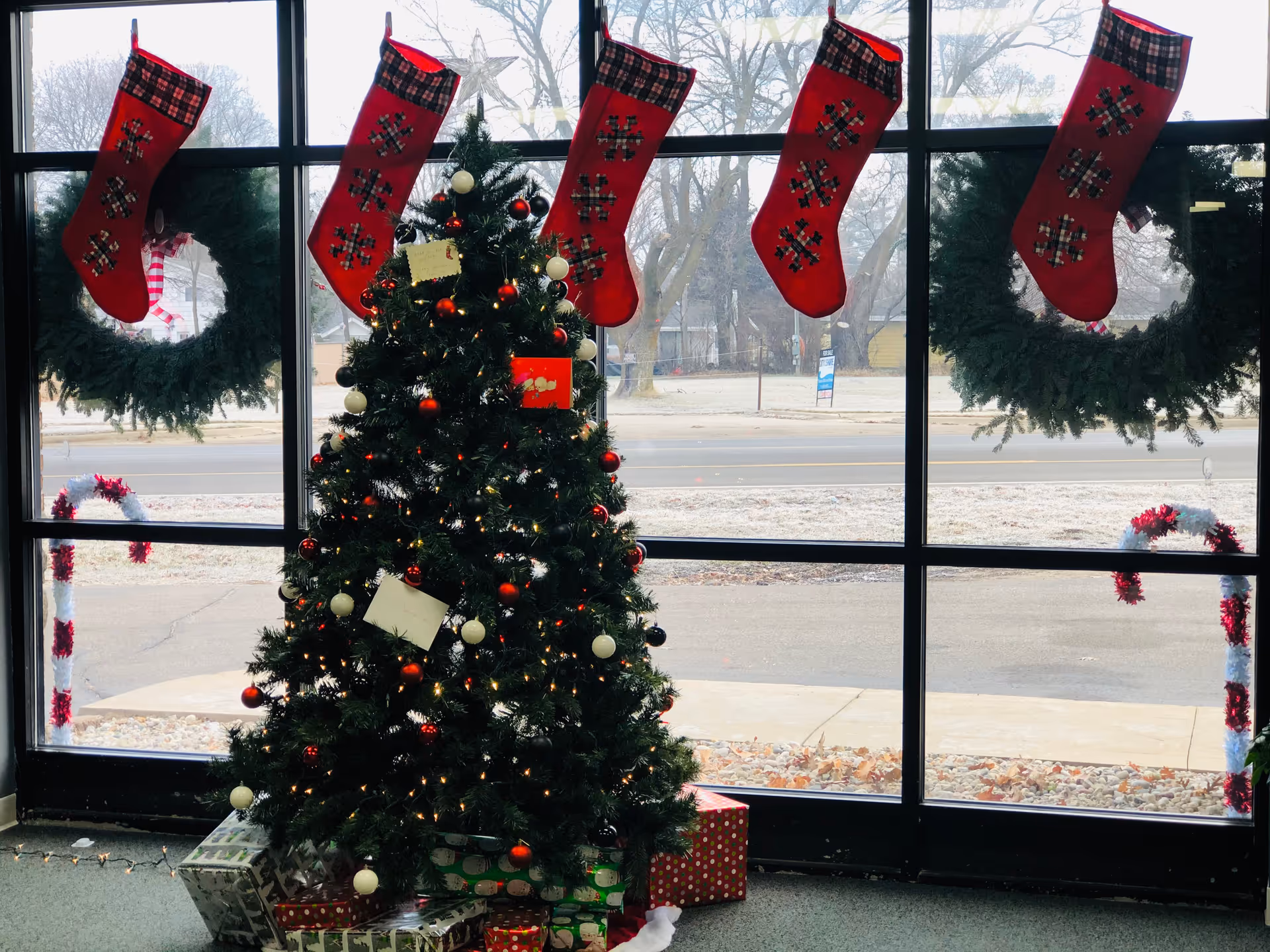 Interior lobby with Christmas tree, wreaths, and stockings hung along large windows.