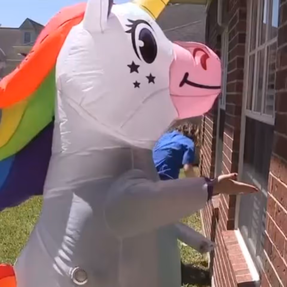 Large inflatable unicorn near a brick building entrance with a person nearby.