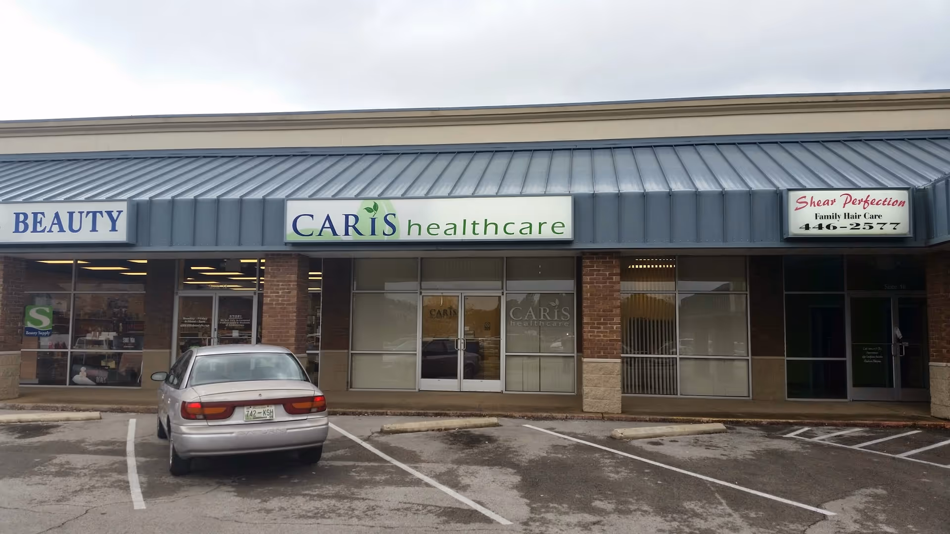 Exterior storefront row featuring Caris Healthcare sign and a parked car.
