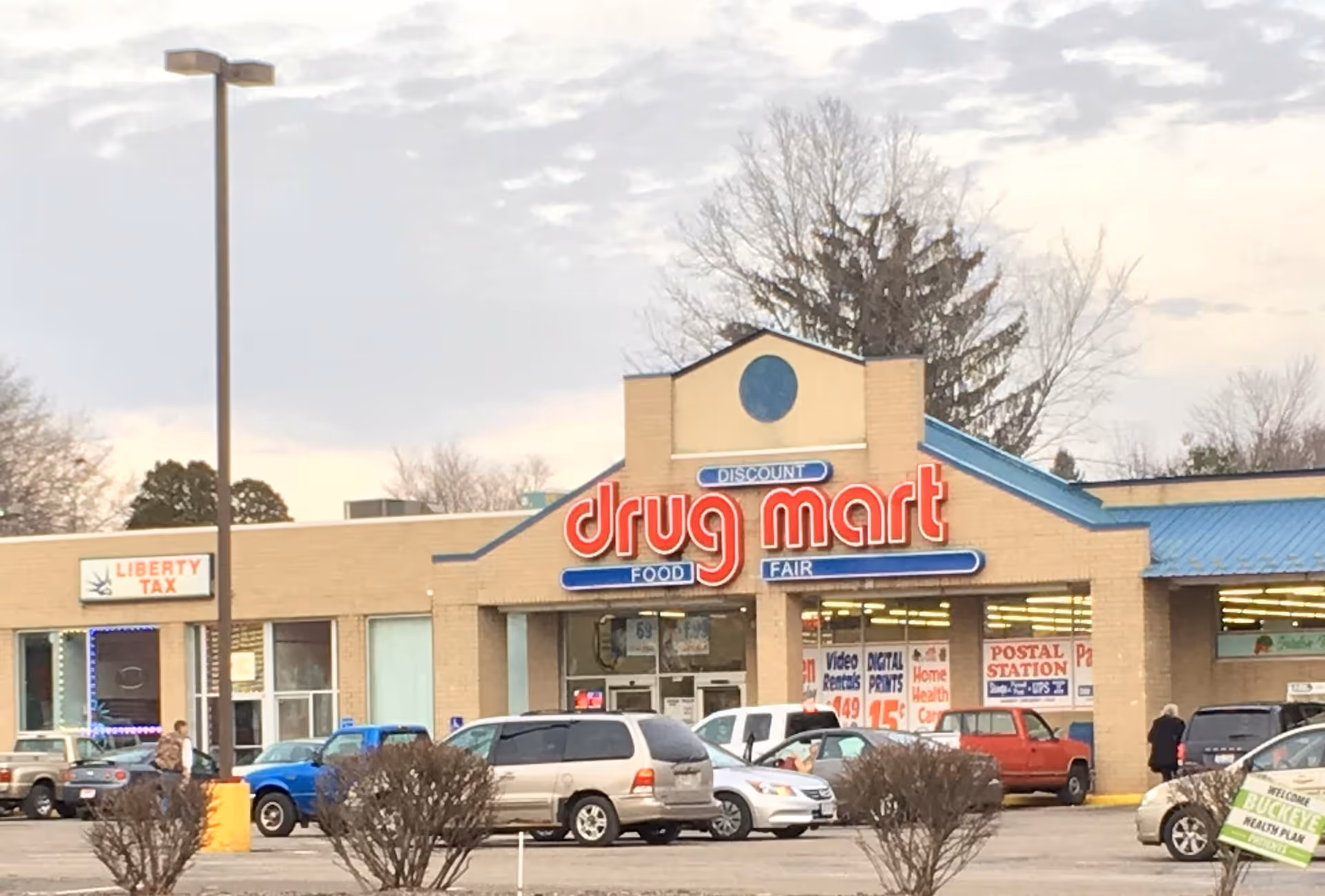 Exterior view of Discount Drug Mart storefront with several cars in the parking lot.