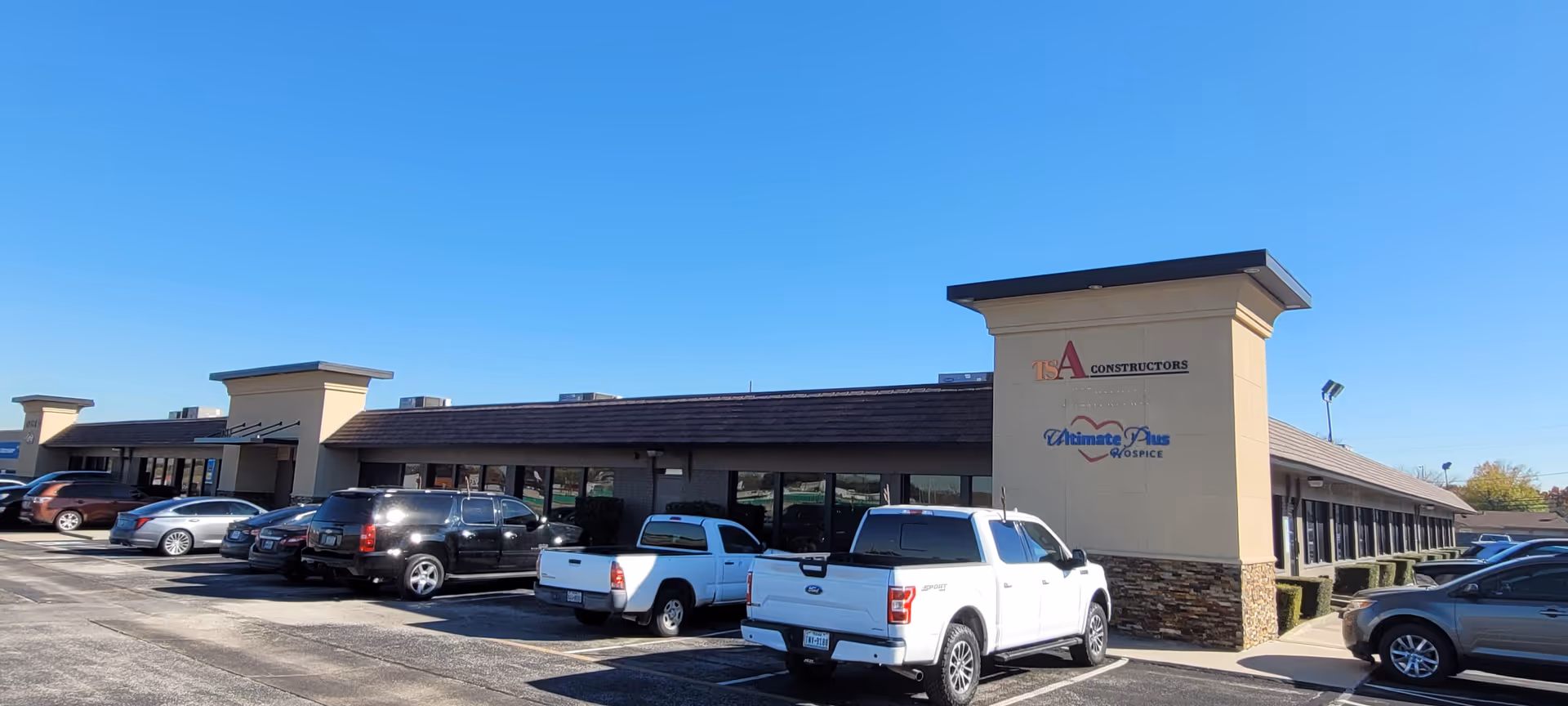 Exterior view of Cornerstone Caregiving building with parked cars along the lot and clear sky.