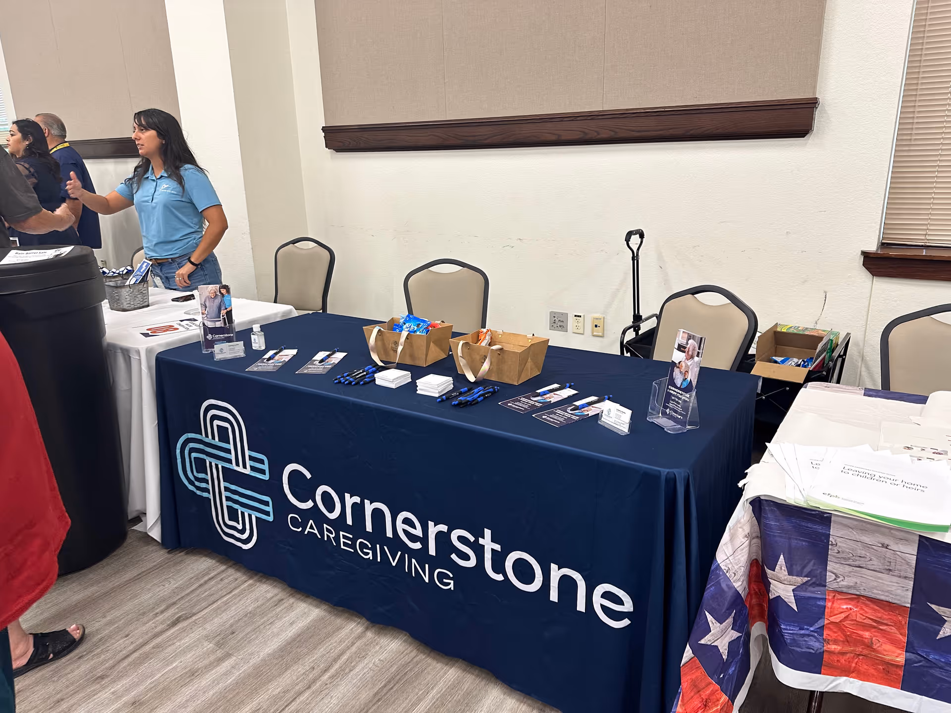 Indoor Cornerstone Caregiving booth with a table, banner, and staff.