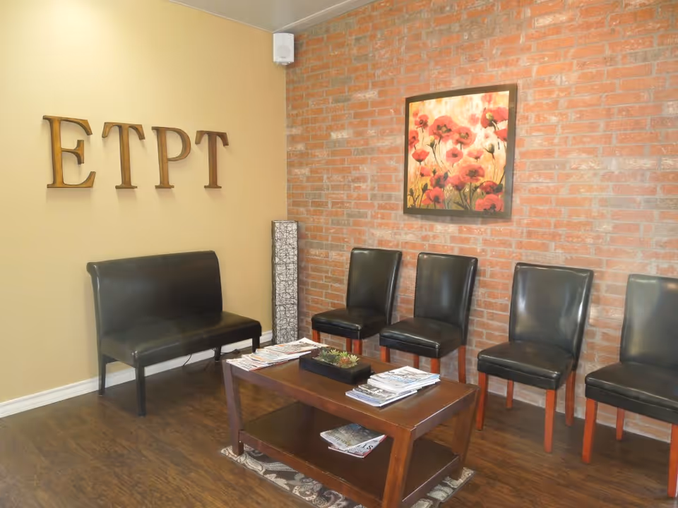 A waiting area with black leather chairs, a coffee table, and a brick wall.
