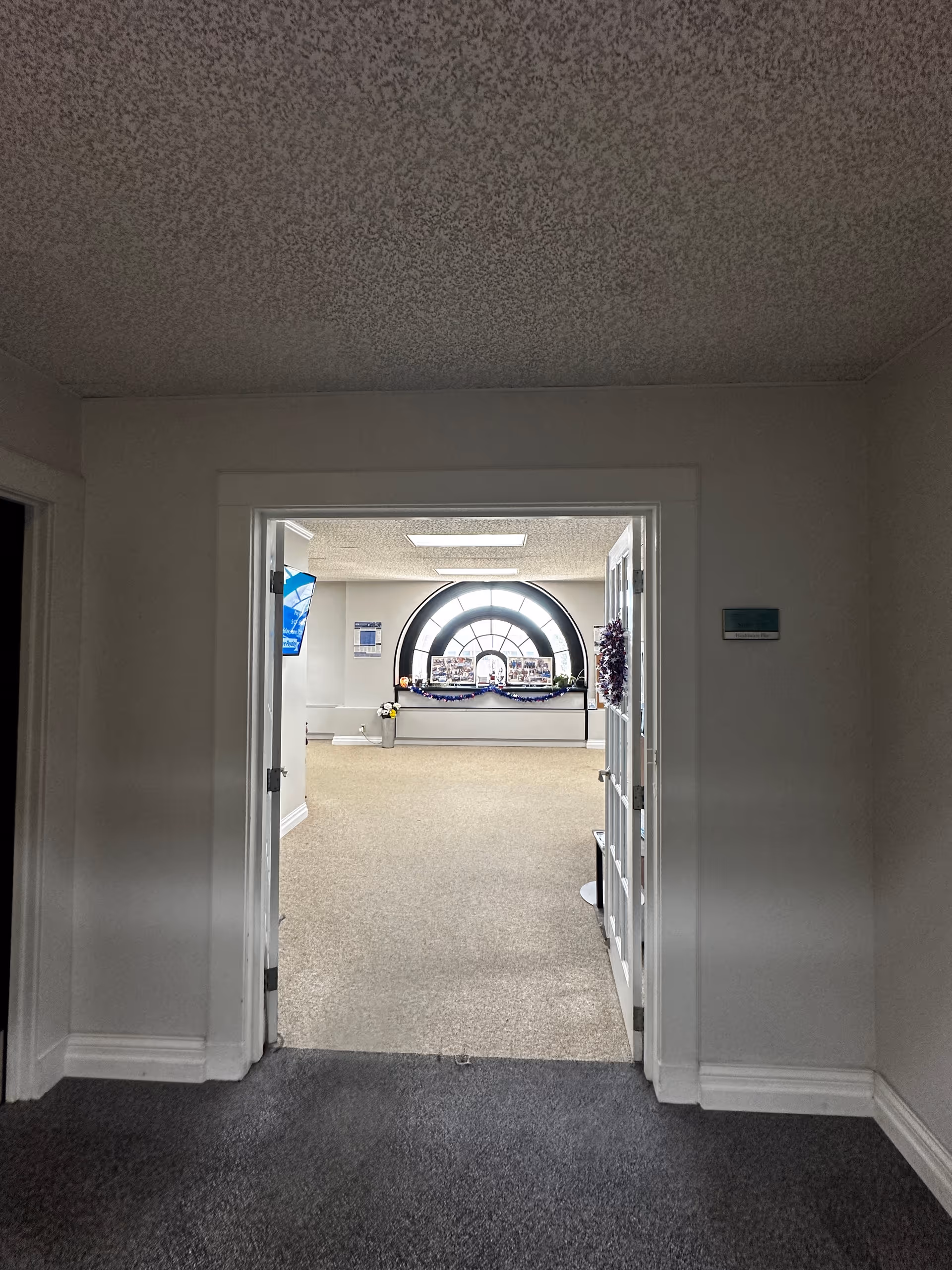 Hallway opens to a reception area featuring a round window and festive garland decor.