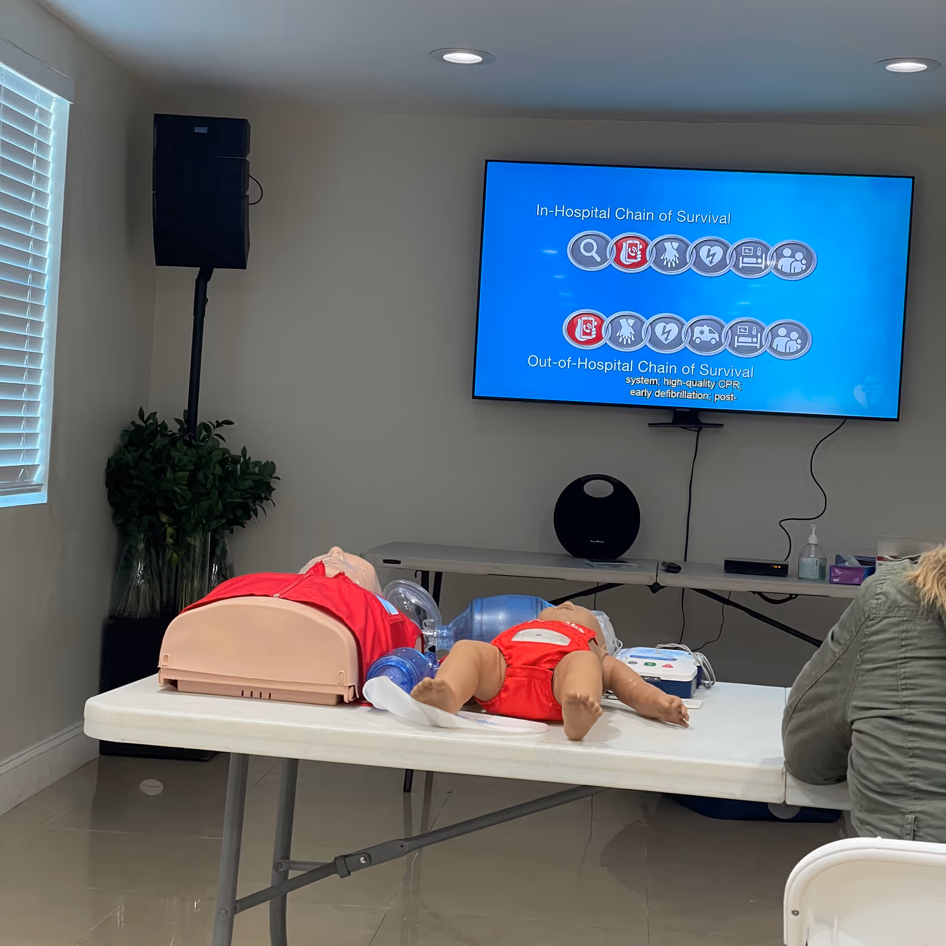 Interior training room with CPR mannequins on a table and a presentation screen.