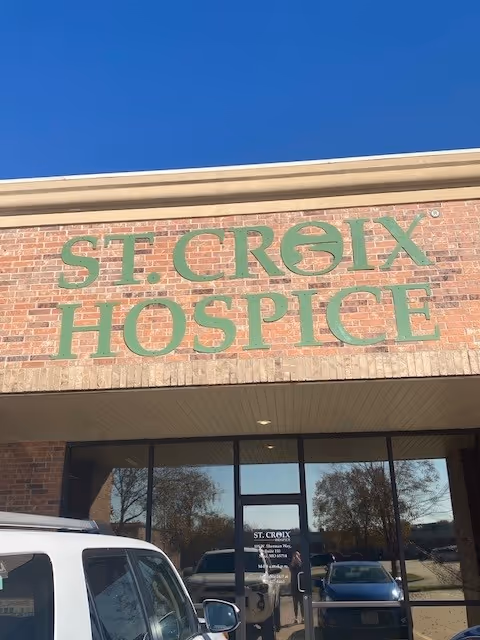Brick-front building with large green St. Croix Hospice sign and glass entrance.