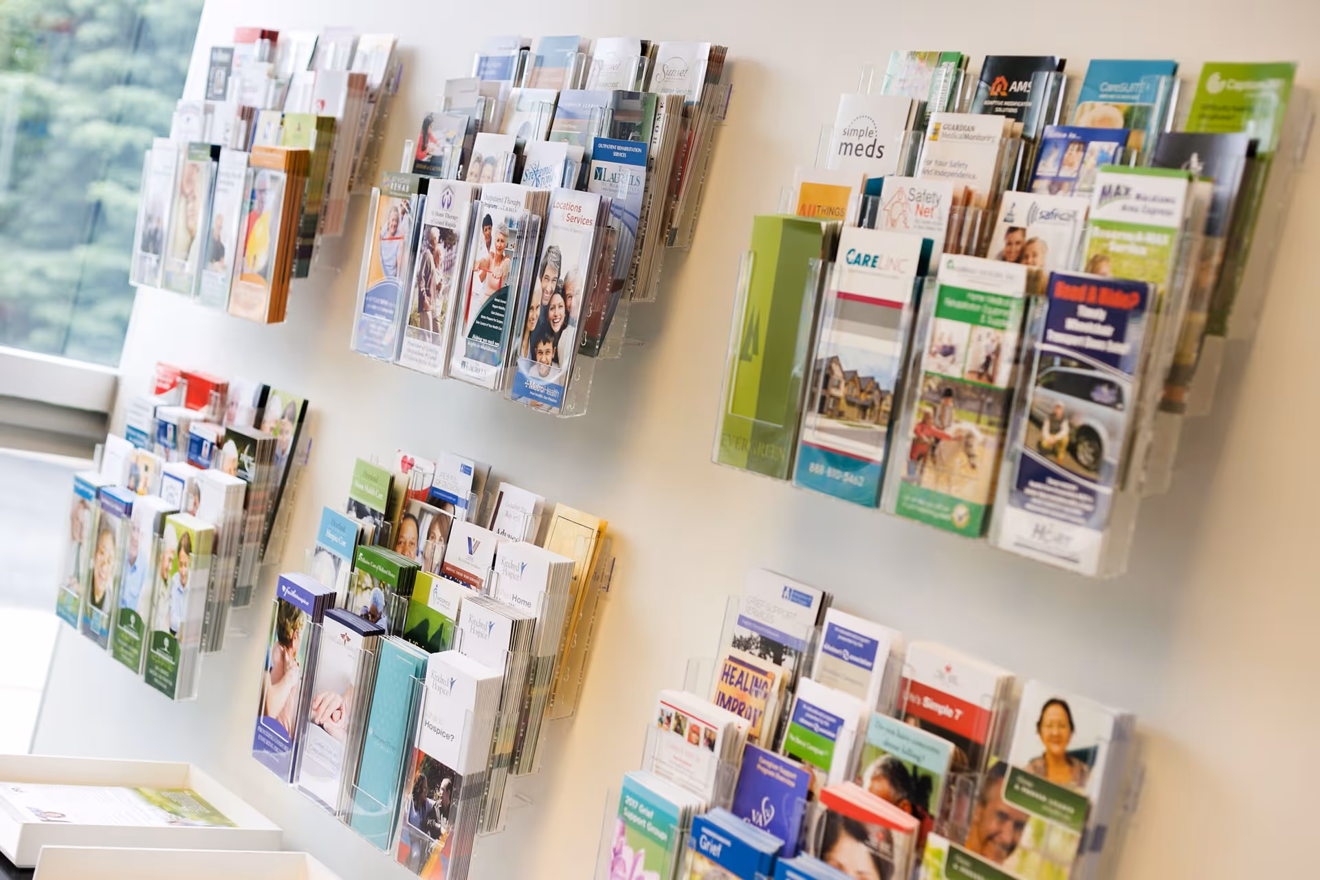 Interior wall with brochure racks displaying colorful medical and senior care pamphlets.