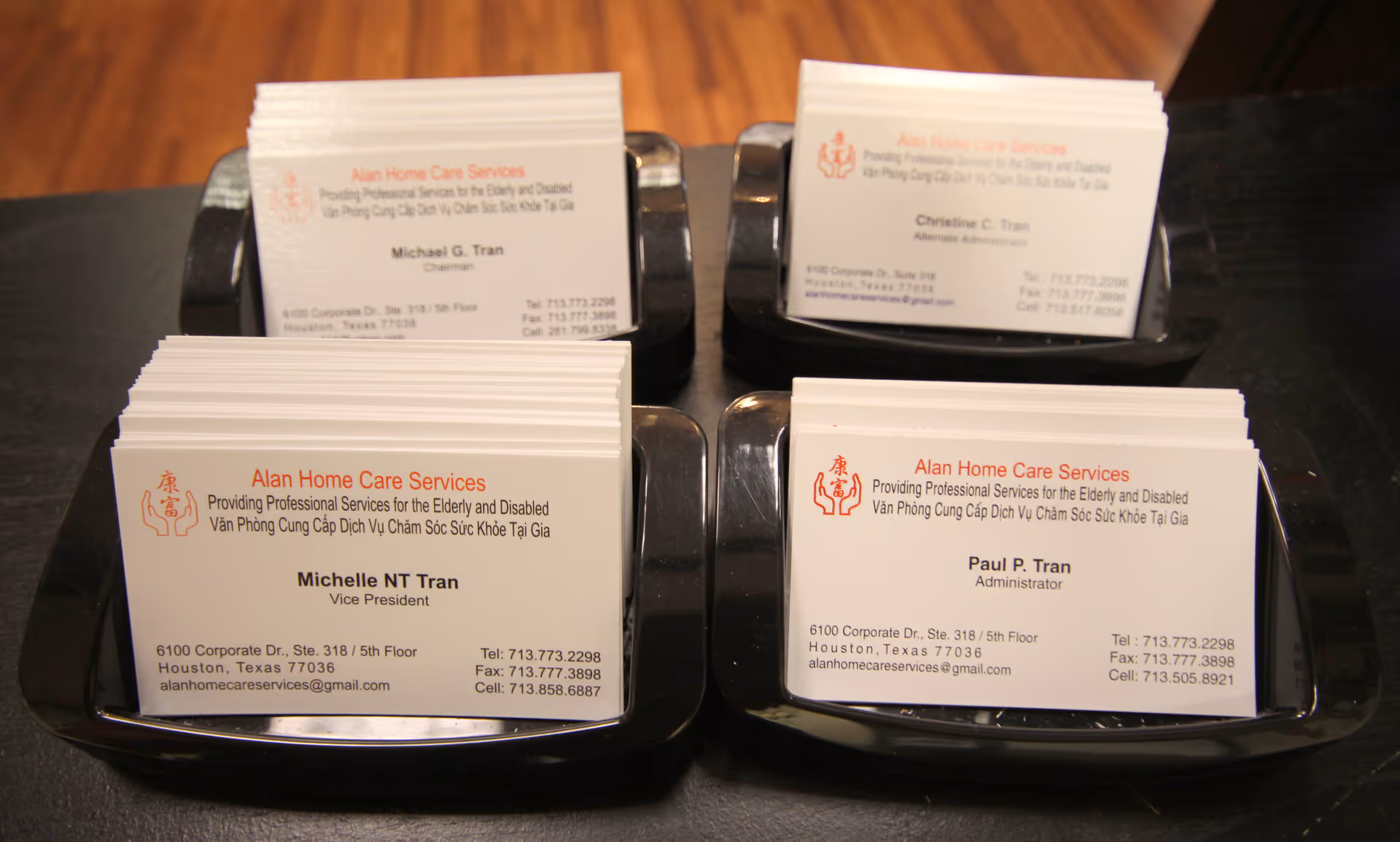 Stacks of Alan Home Care Services business cards in card organizers on a dark counter.