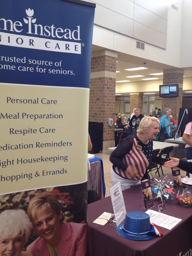 Promotional banner for Home Instead displayed at an indoor senior care event.