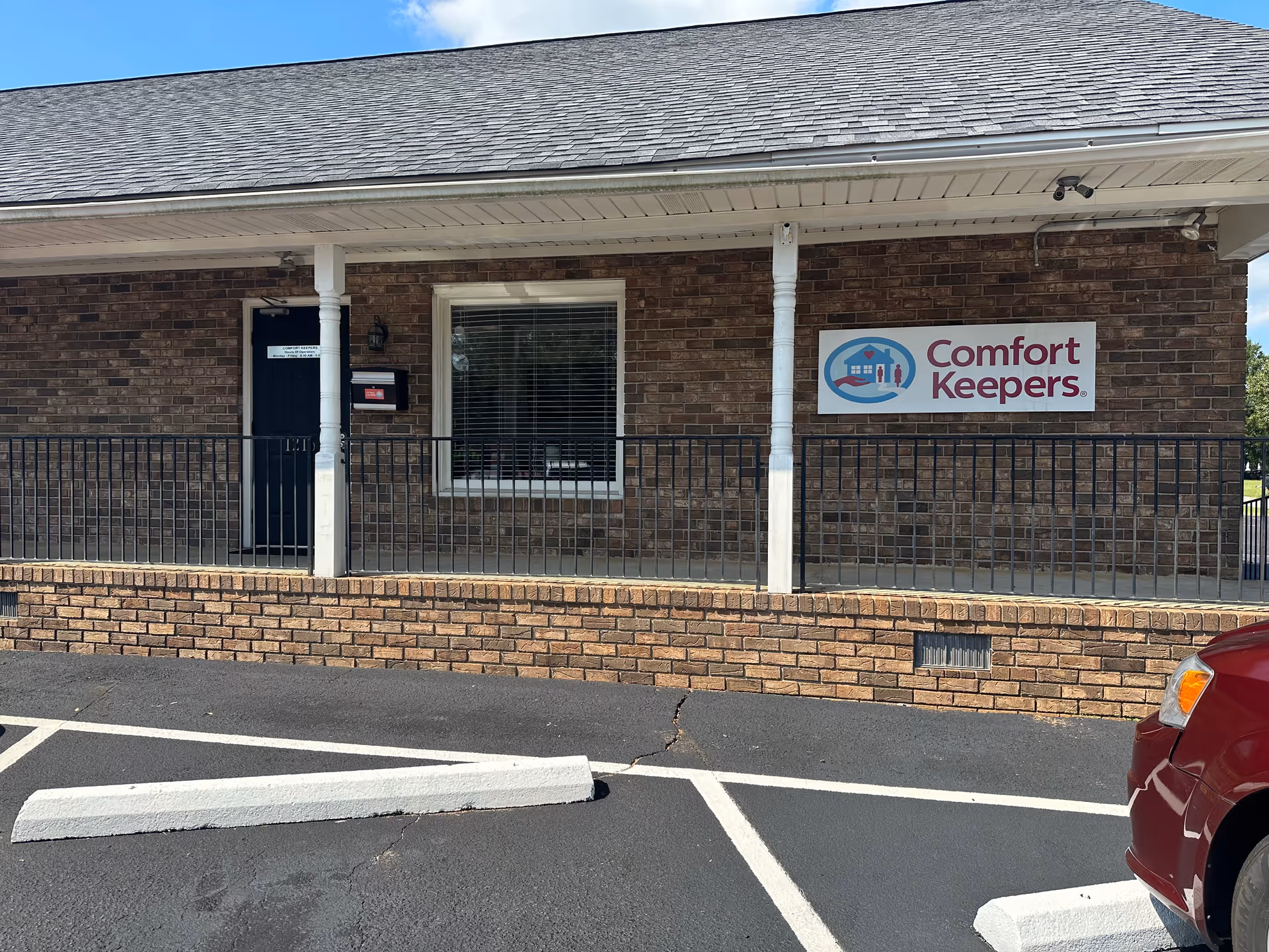 Brick facility exterior with a Comfort Keepers sign and a parking lot.