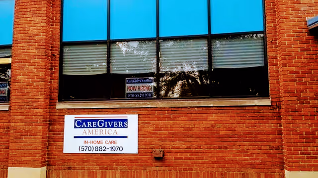 Brick exterior of a CareGivers America building with a hanging sign.