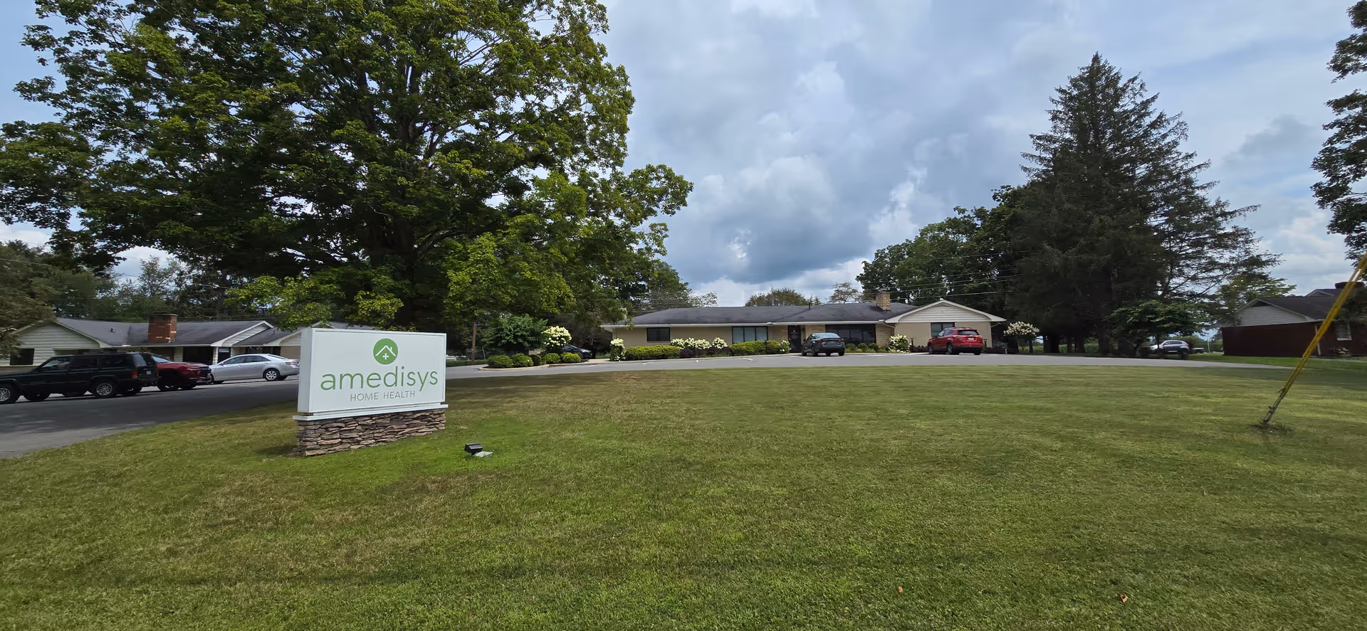 Exterior view of Adoration Home Health facility with green lawn and sign.