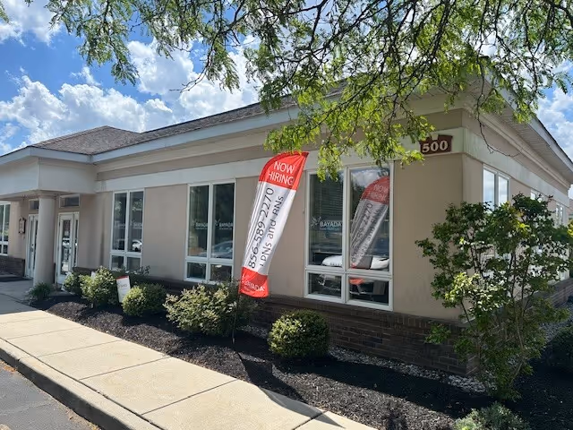 A single-story beige building with BAYADA signage, large windows, Now Hiring banners, and landscaping.