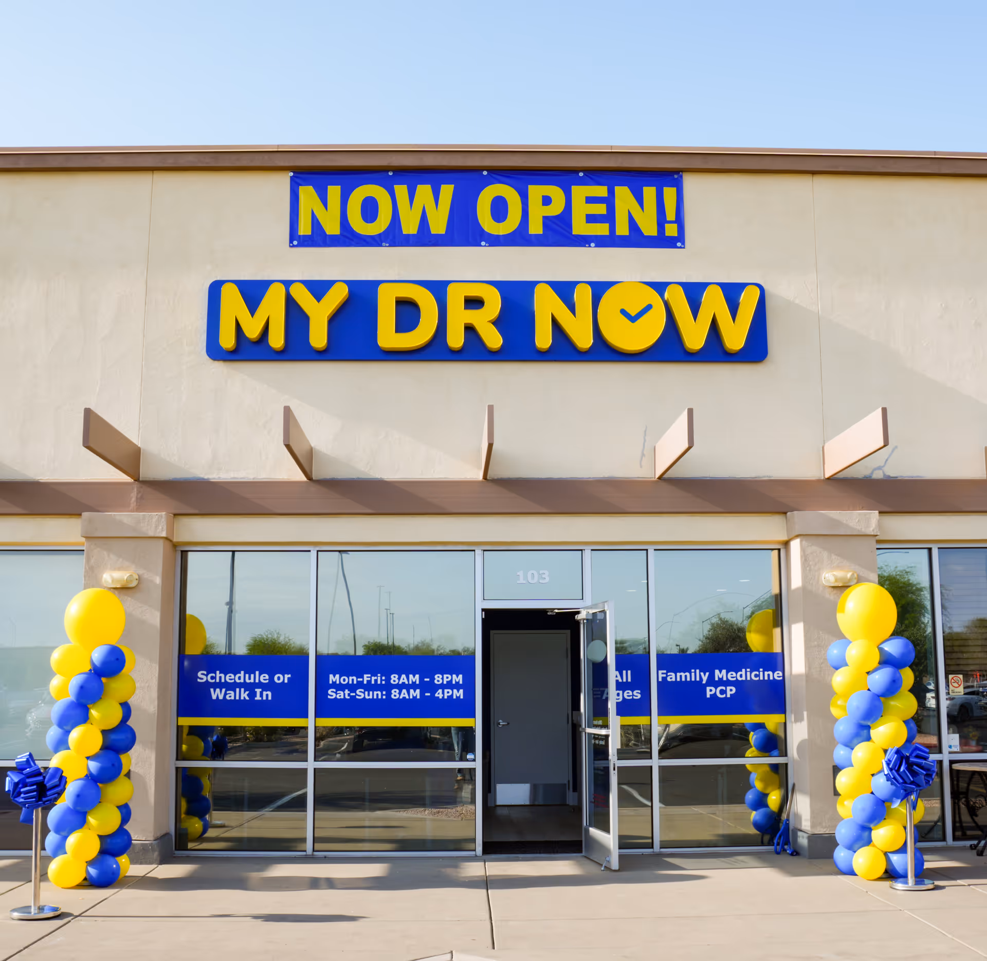 Exterior of a clinic with NOW OPEN and MY DR NOW signs, glass doors, and balloons.