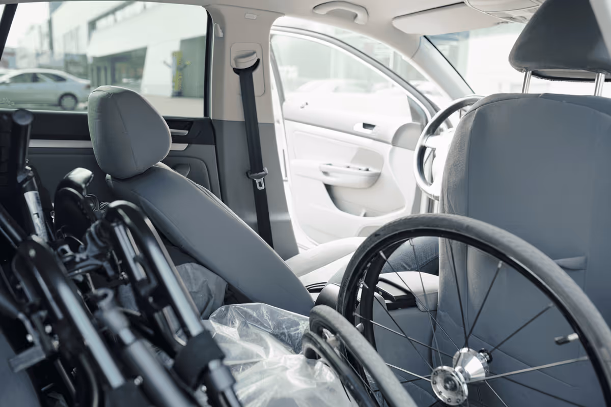 Interior of a car with a wheelchair and open front passenger door.