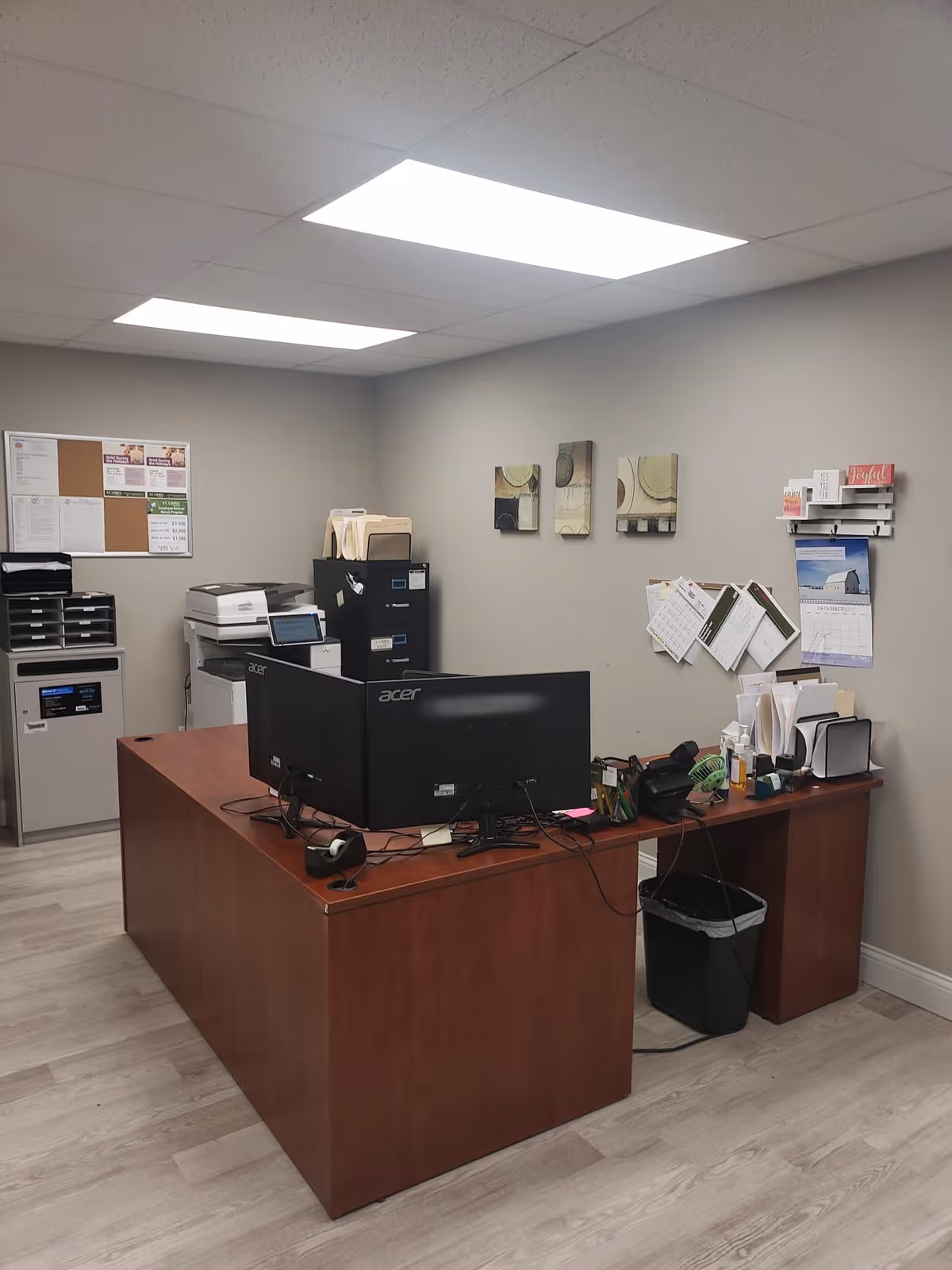 Small office area with a wooden desk, dual computer monitors, and office supplies.