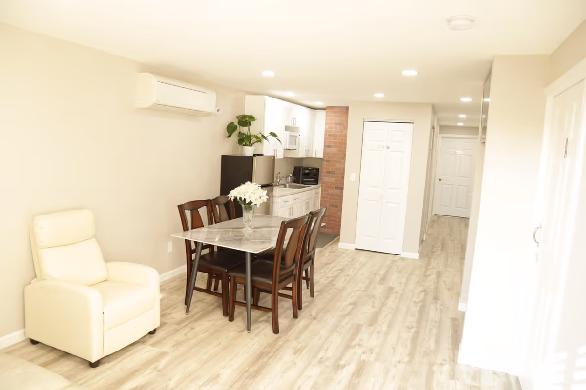 Bright open dining and kitchen area with a marble table and beige seating.