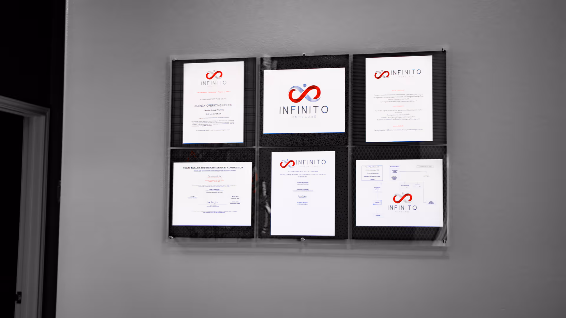 Wall-mounted certificates and Infinito Homecare logo boards displayed in a hallway.