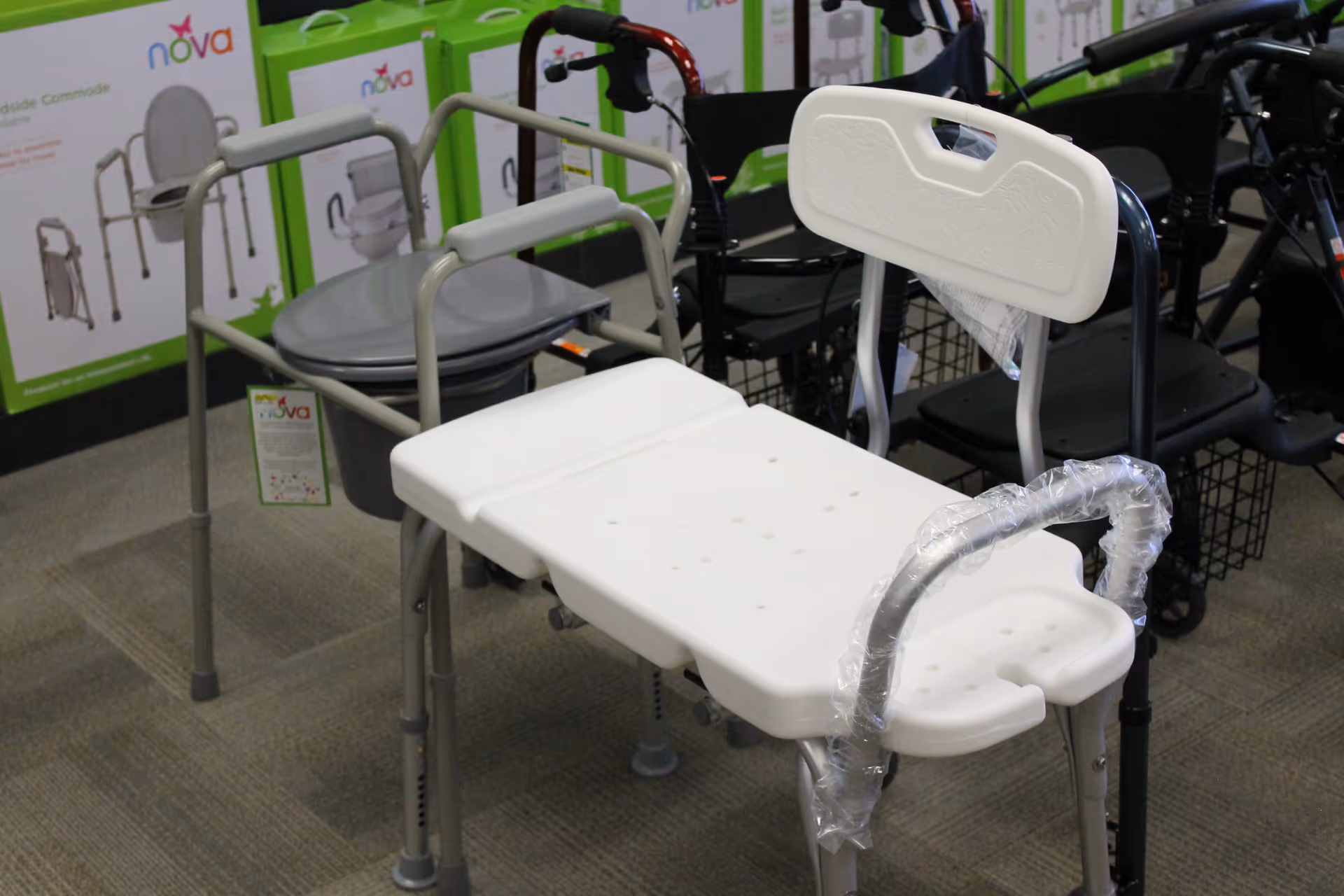 White shower/commode chair with backrest and armrests in a medical supply showroom.