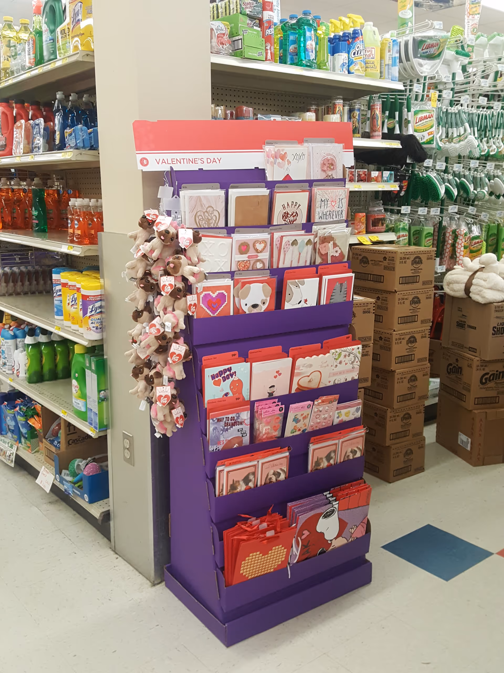 A purple card display in a drugstore aisle with Valentine's Day cards.