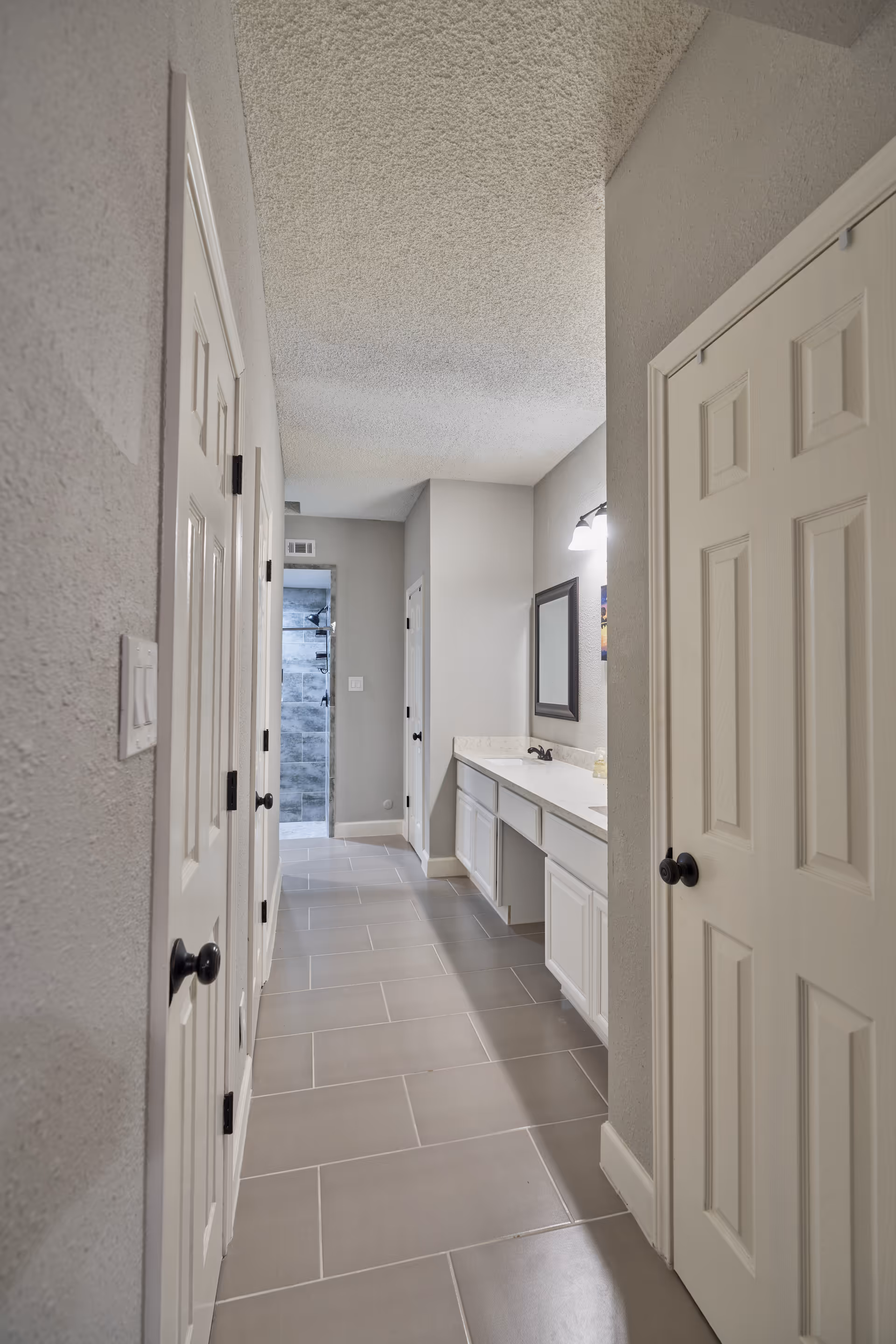 Narrow hallway in a senior living facility with a long tiled floor and a bathroom vanity.