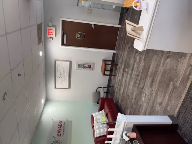 Lobby area of BAYADA Adult Nursing with red sofa, doorway, seating, and wall decor.